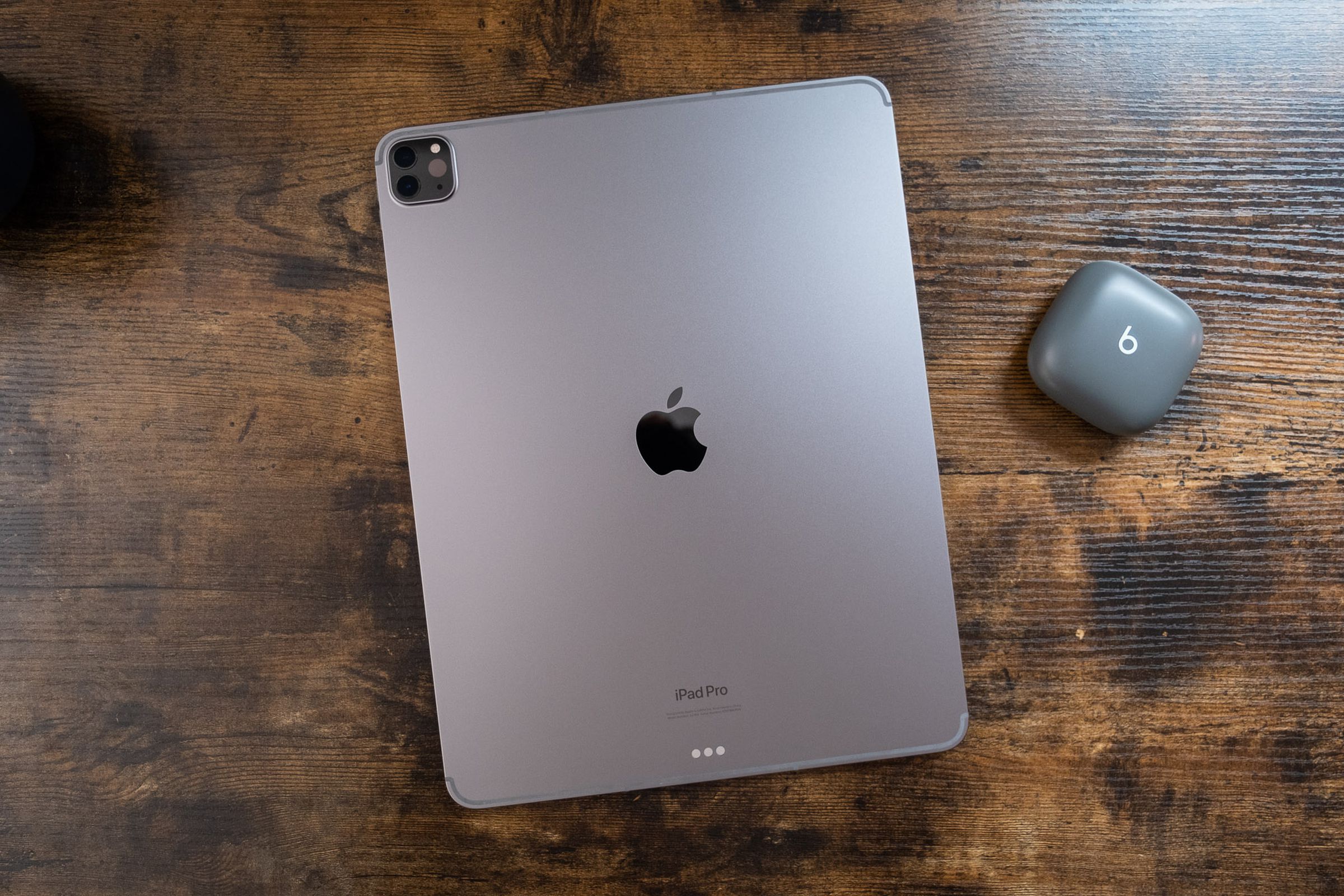 جهاز iPad Pro مقاس 12.9 بوصة رمادي اللون مقلوب على طاولة خشبية ، ويُنظر إليه من أعلى إلى أسفل.
