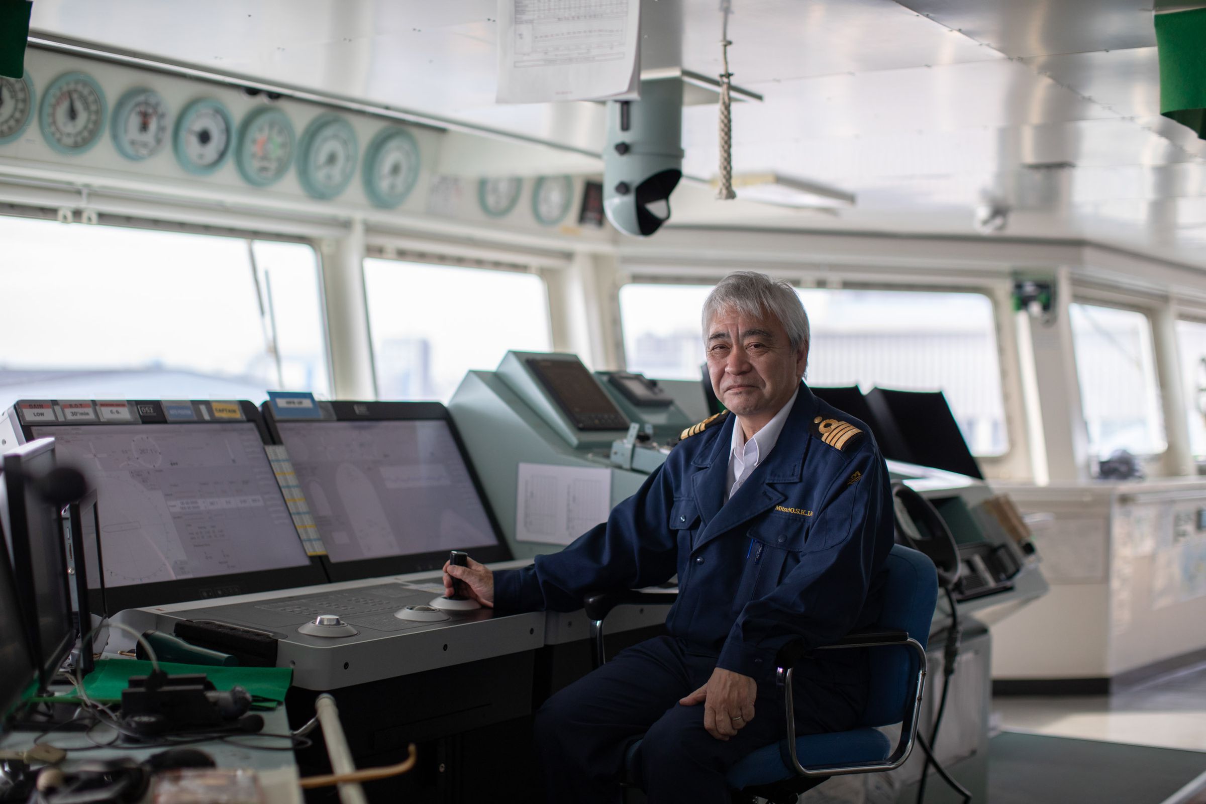 Captain Shoichi Suzuki sits in front of the control panels in the bridge of the Ocean Link.