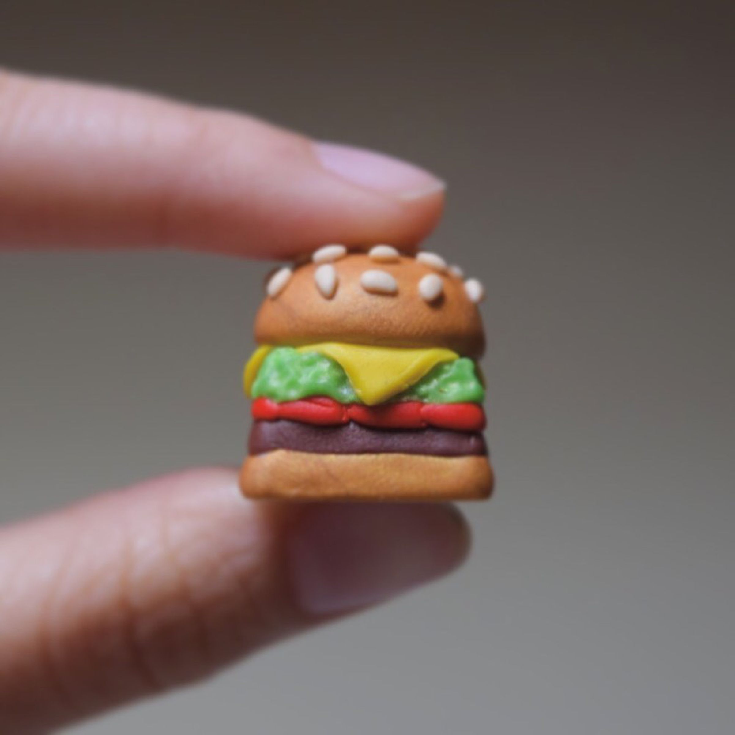 A tiny keycap resembling a burger is held between two fingers.