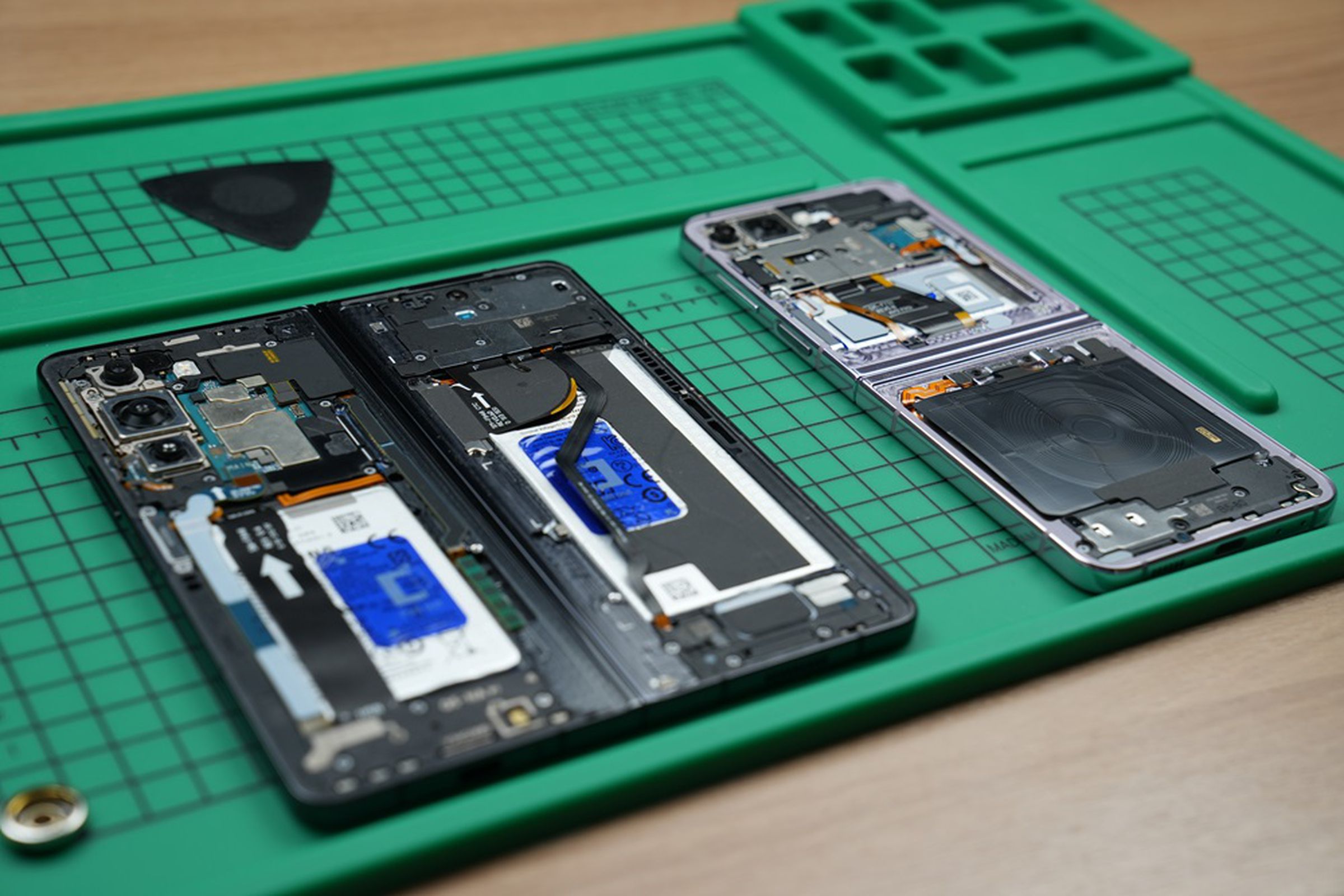 The insides of two smart phones on a green mat.
