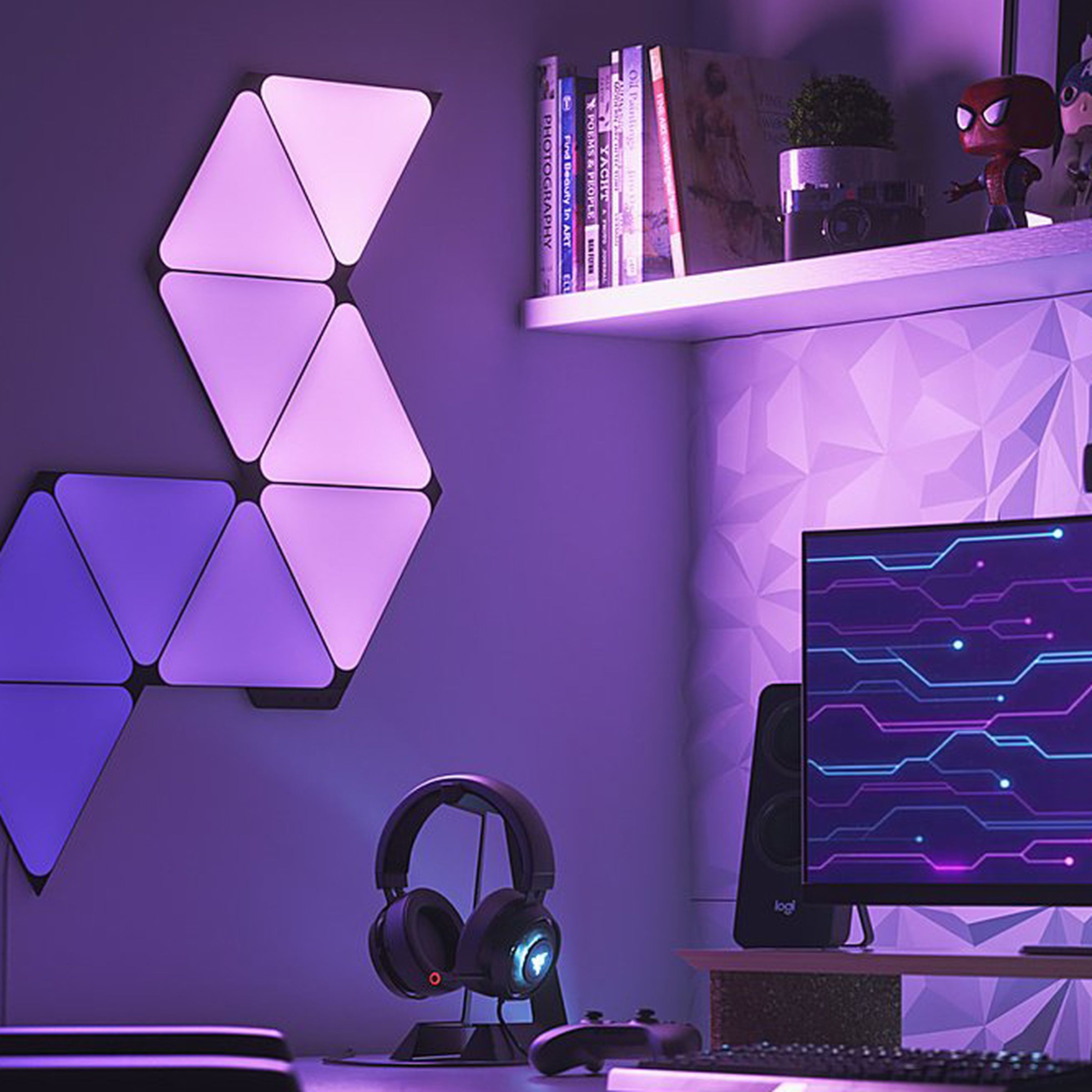 A series of glowing Nanoleaf light panels on a wall beside a pair of headphones and a computer monitor.
