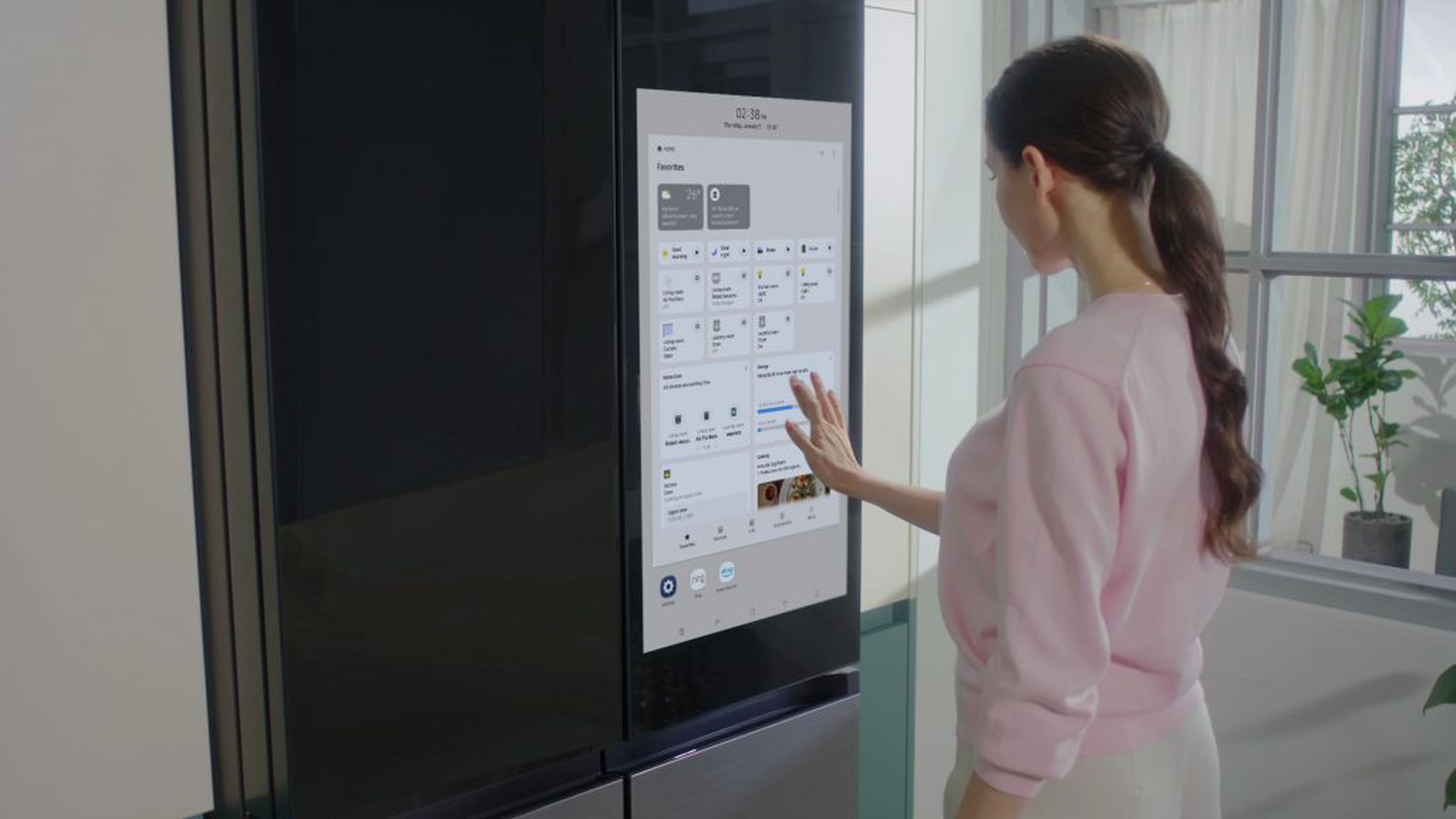 Una mujer usando el refrigerador Samsung Bespoke Refrigerador Family Hub Plus.  Ella está ajustando los controles en la pantalla táctil en una cocina limpia.