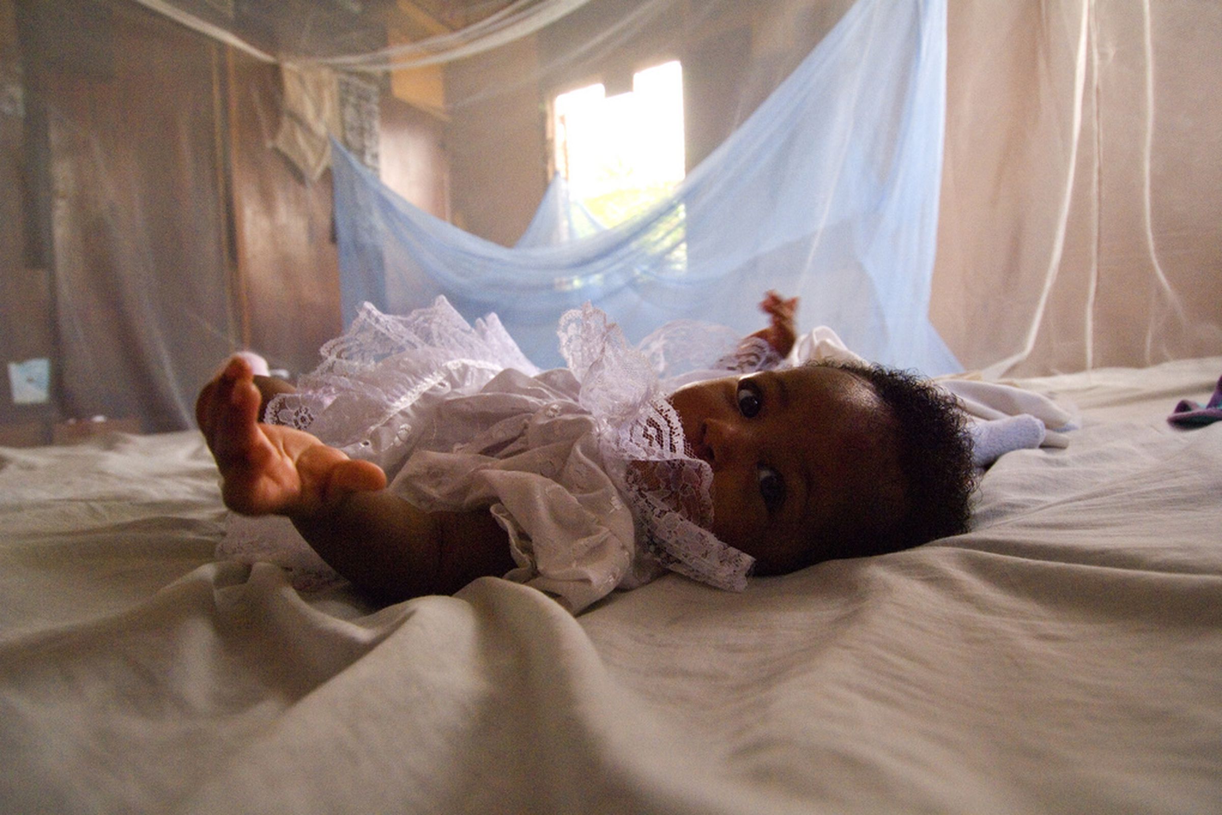 Infant surrounded by malaria bed net