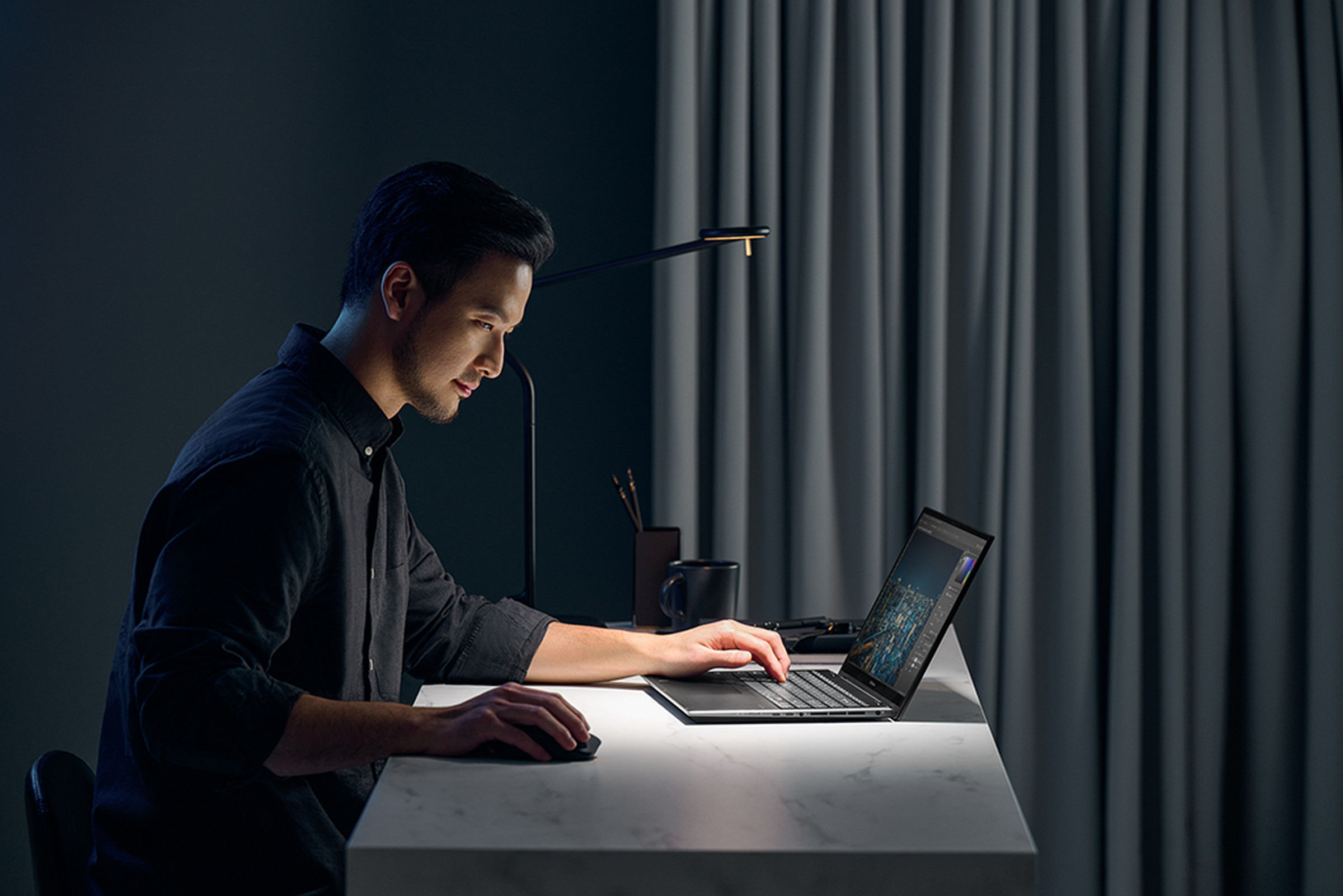 A user navigates with the Zenbook Pro 15 OLED in a dark office space.