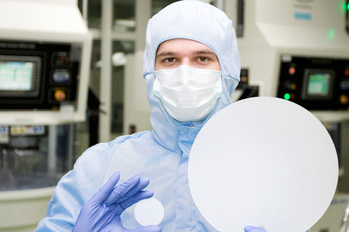 A clean room staff member holding up a Sapphire wafer.