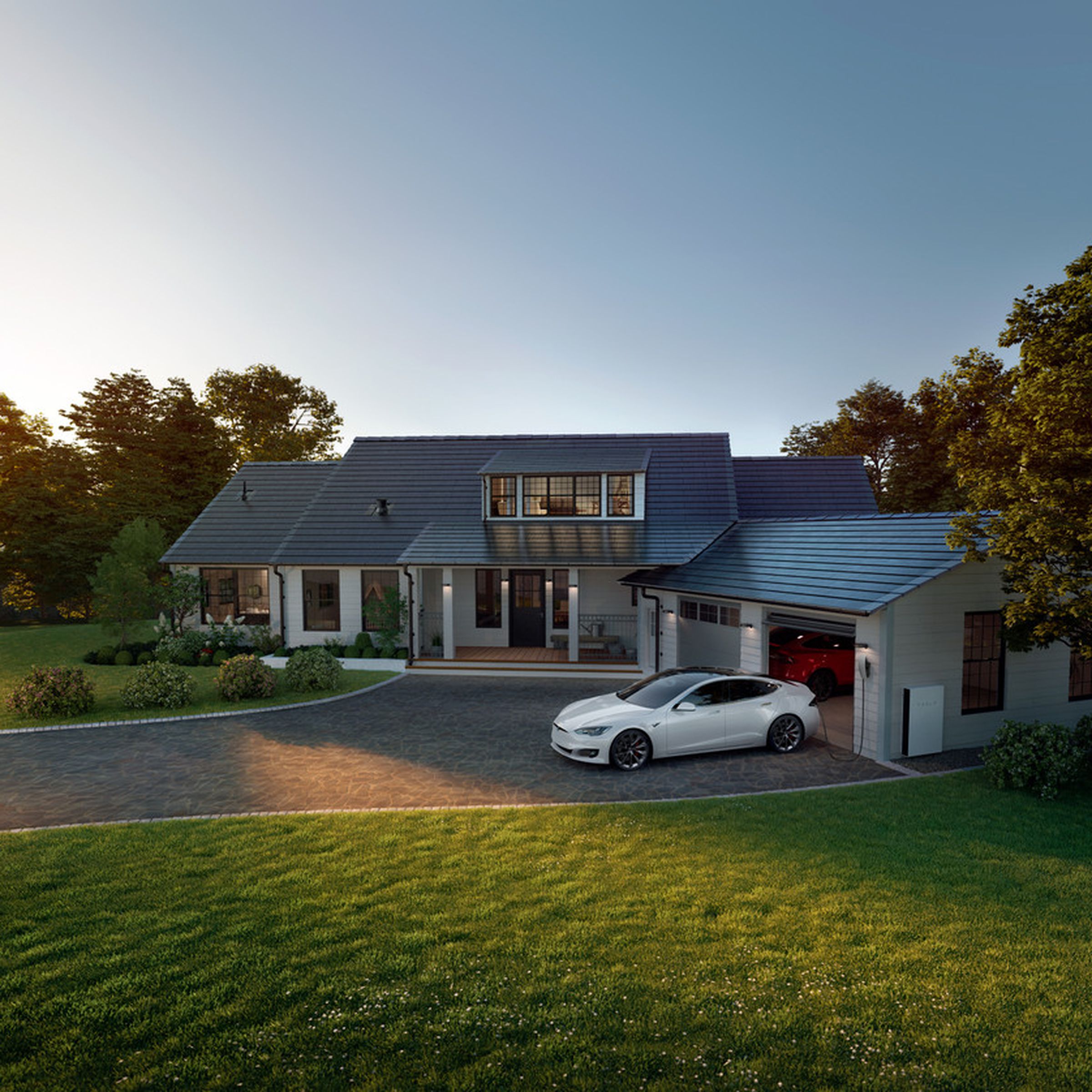 Zoomed-out view of a house with shiny shingles on top, which is the Solar Roof, and there is a white Tesla Model S in the driveway with one of two garage doors open and a Tesla Powerwall battery installed outside the house