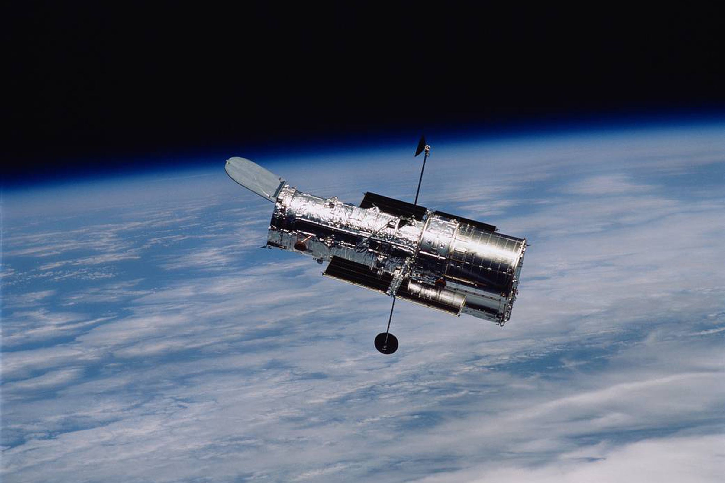 Hubble is in the foreground, the curve of the earth is in the background