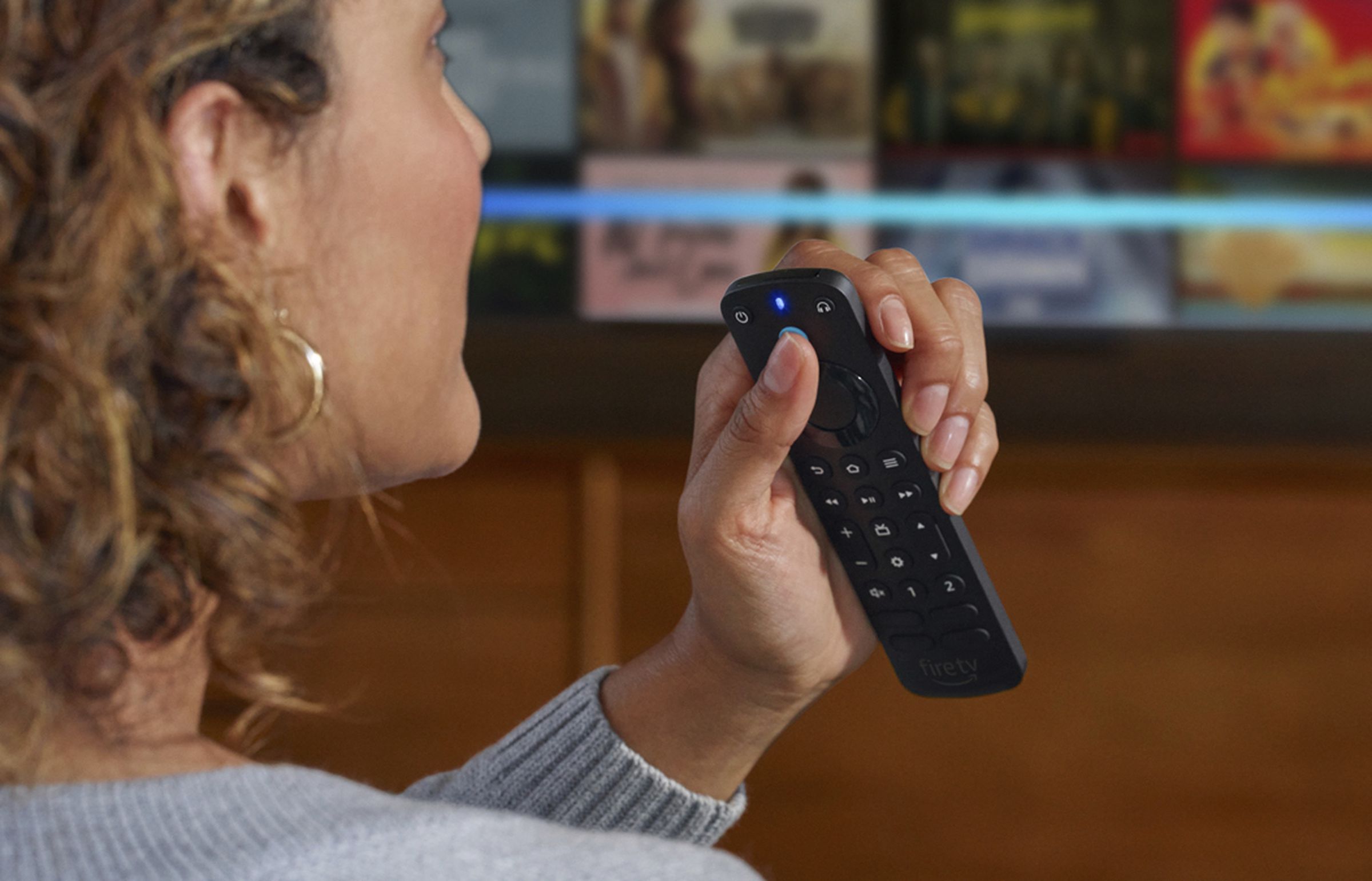 An image of a woman speaking voice commands to Amazon’s Alexa Voice Remote Pro while holding it in her left hand.