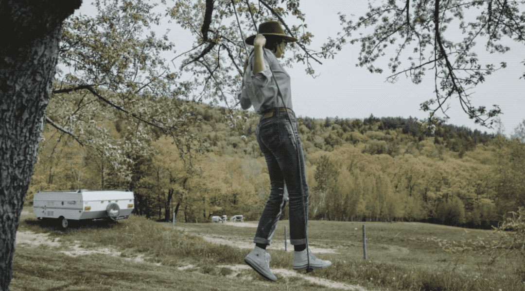A GIF demonstrating the new content-aware heal tool in Adobe Lightroom being used on a distracting trailer behind a woman on a swing.