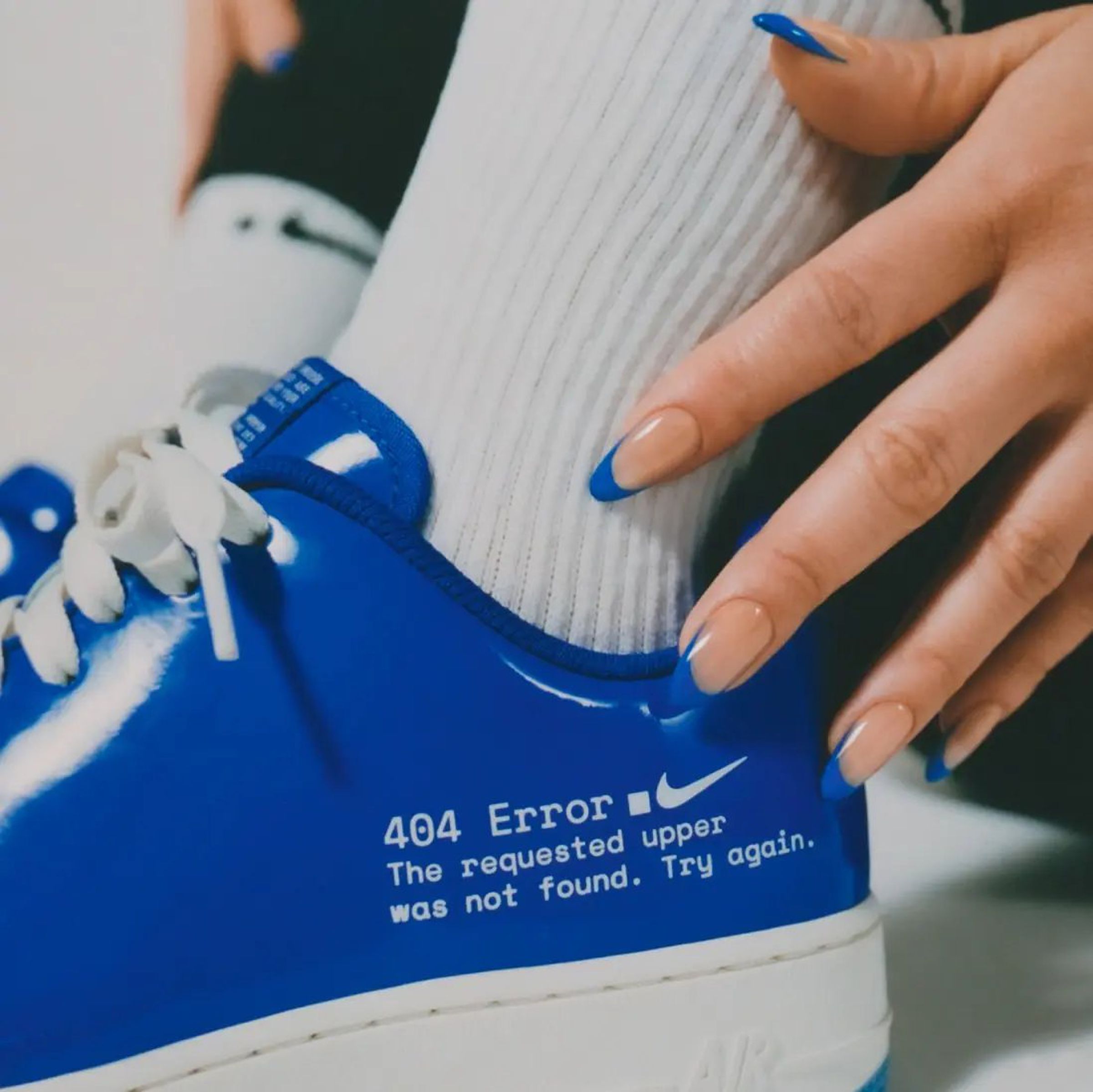 Close-up of blue Nike low-top shoe with print on the side reading “404 Error. The requested upper was not found. Try again.”