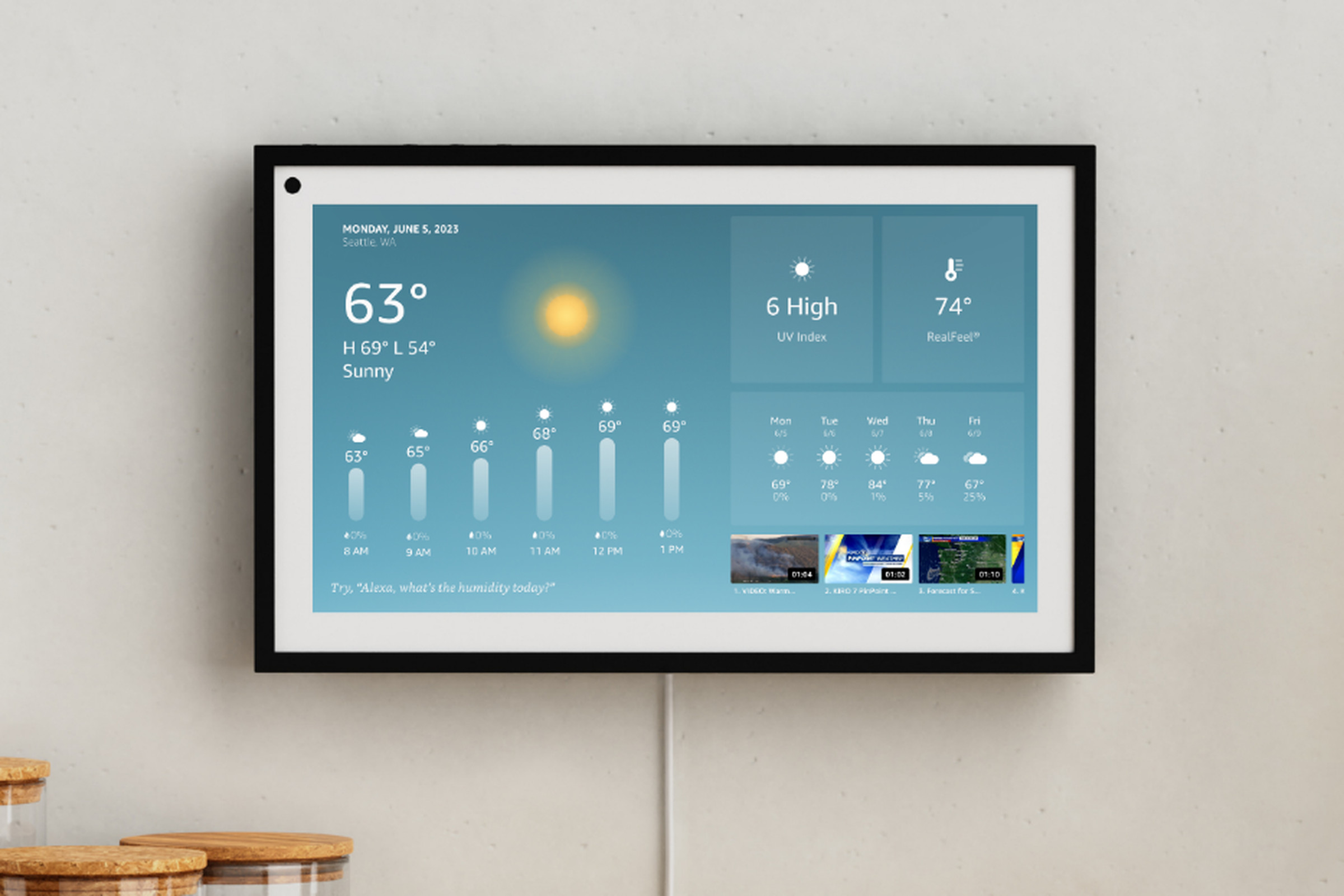An Echo Show 15 mounted on a wall showing the local weather forecast.