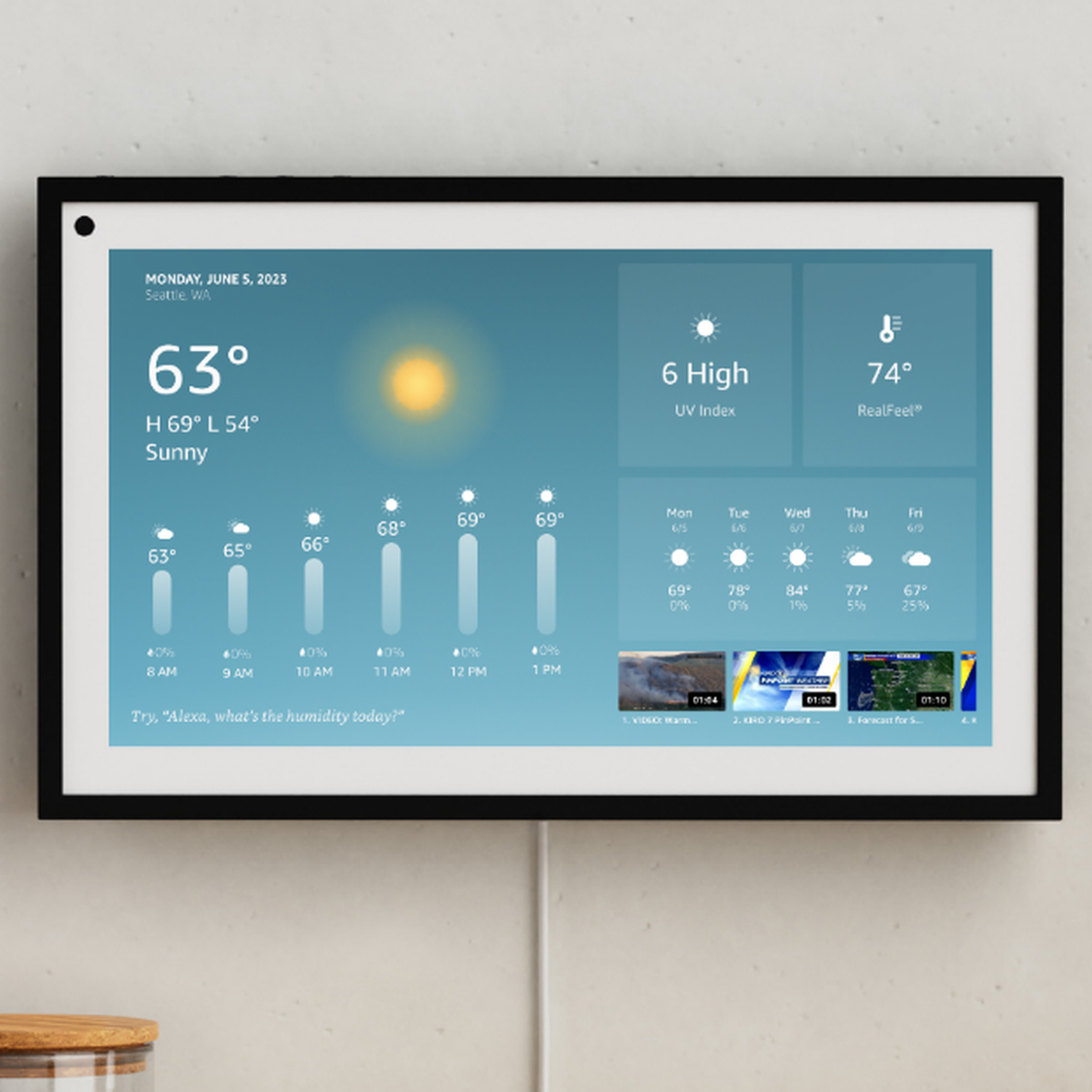An Echo Show 15 mounted on a wall showing the local weather forecast.