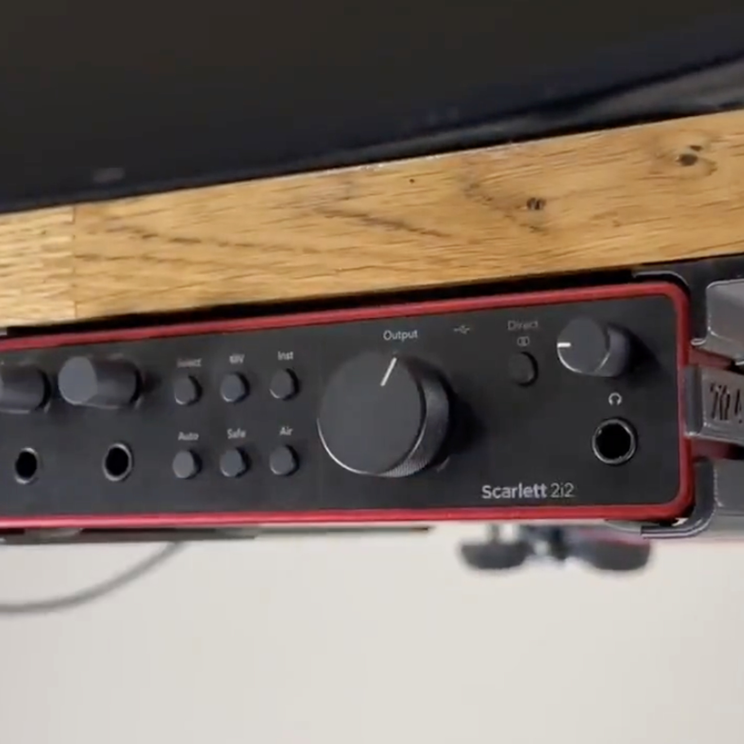 Red audio interface device in a bracket under a desk.