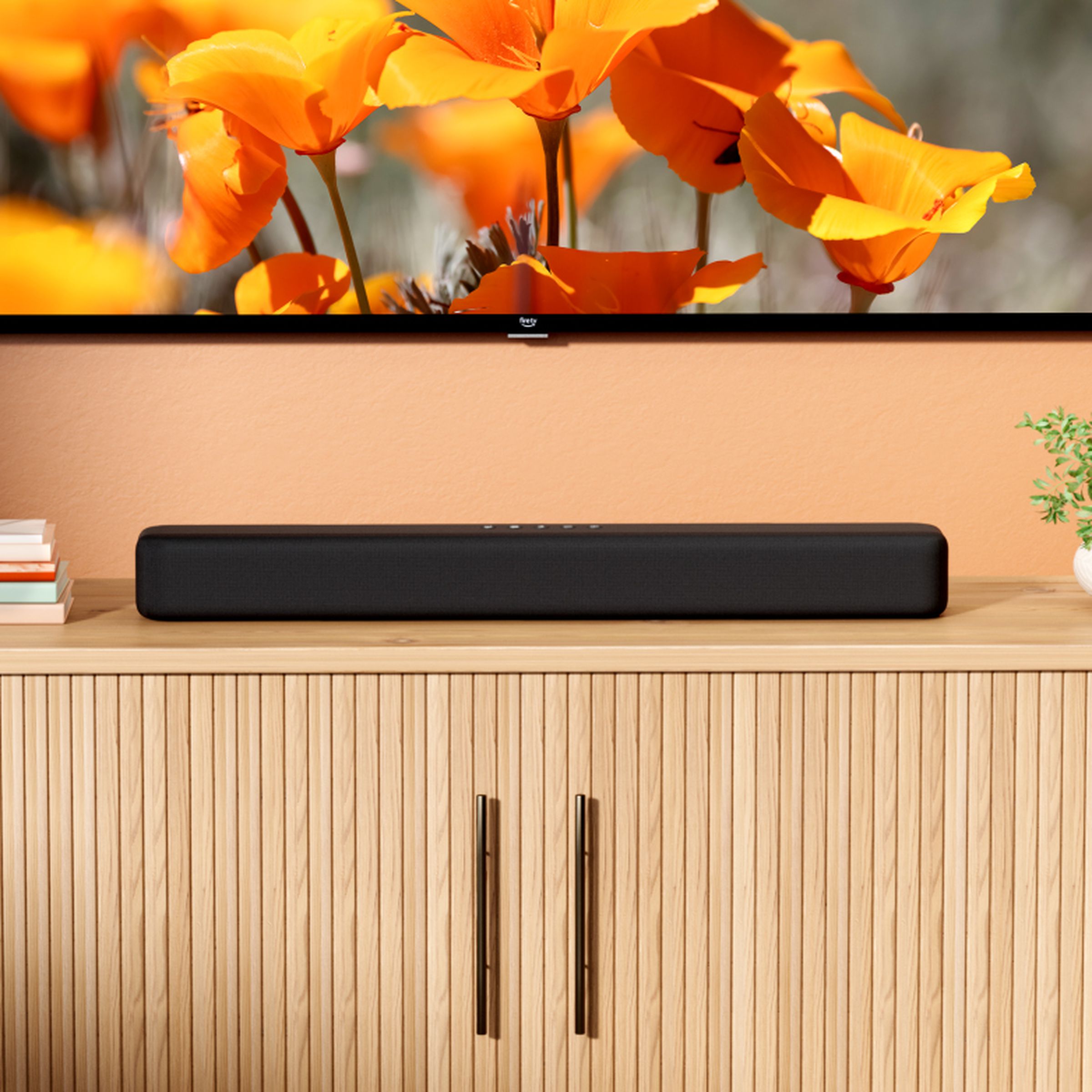 The Amazon Fire TV Soundbar positioned under a TV, sitting on a piece of furniture.