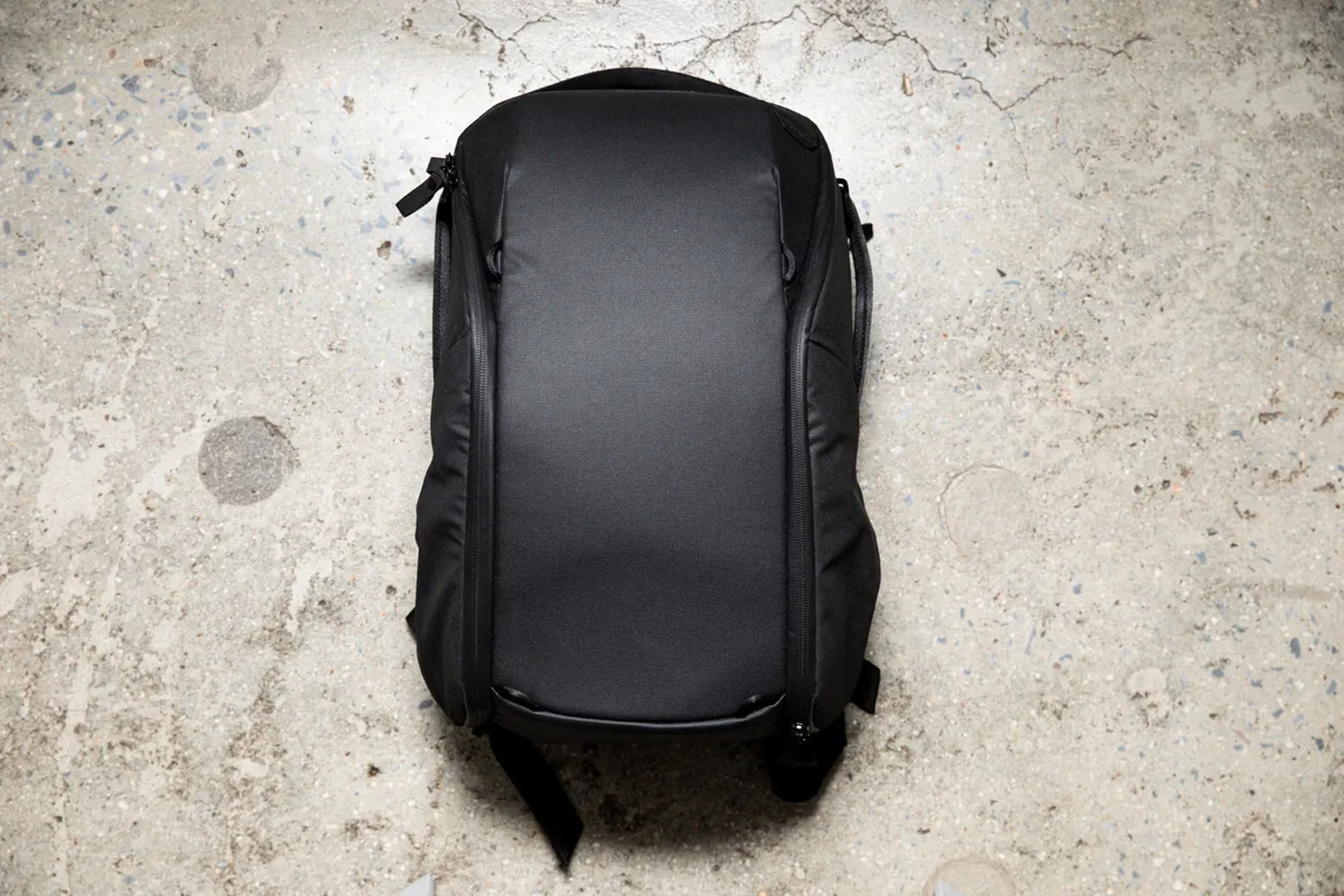 A photo of the black Peak Design Everyday Backpack face-up resting on the floor.
