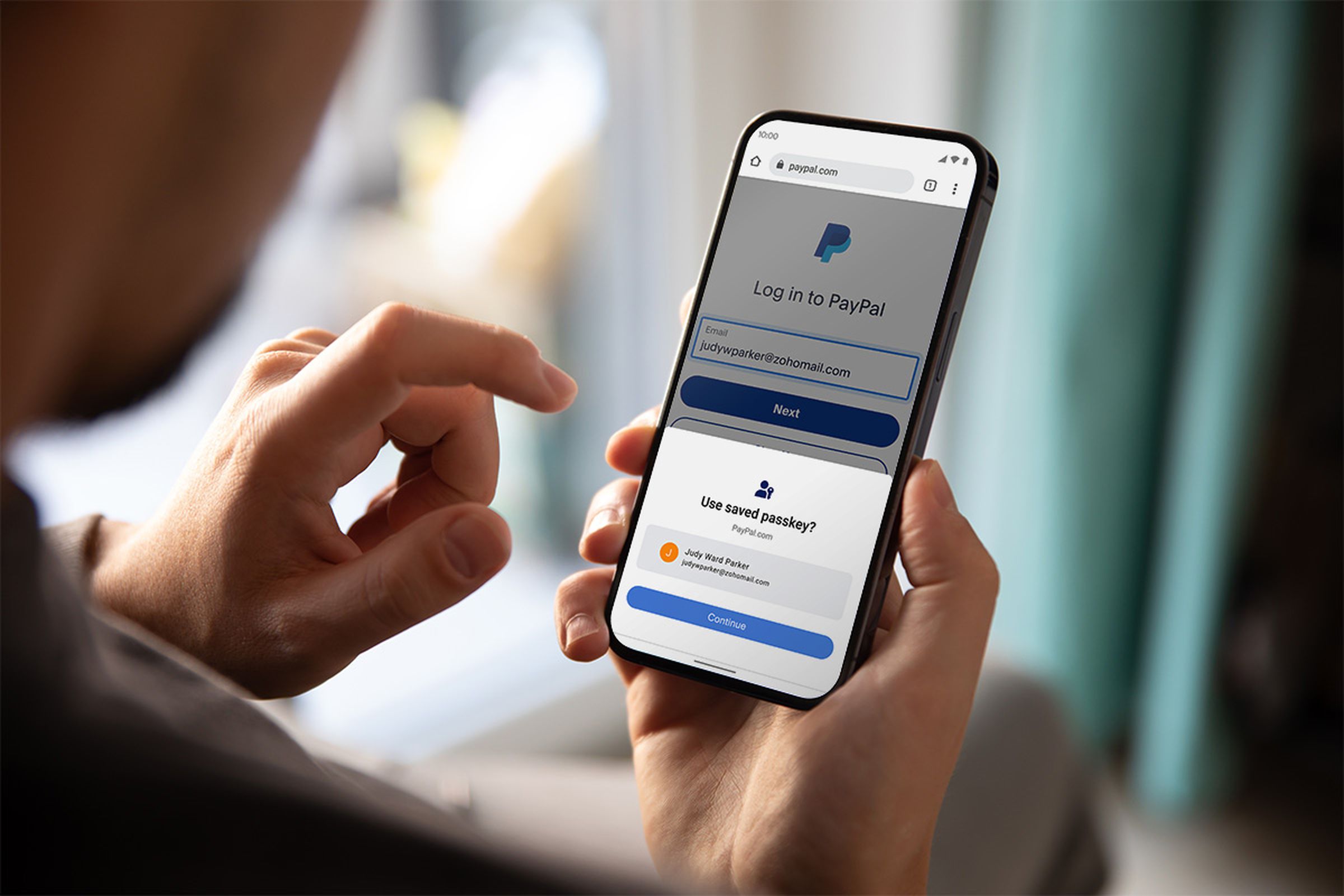 Photo of someone using a phone to log into PayPal with a passkey