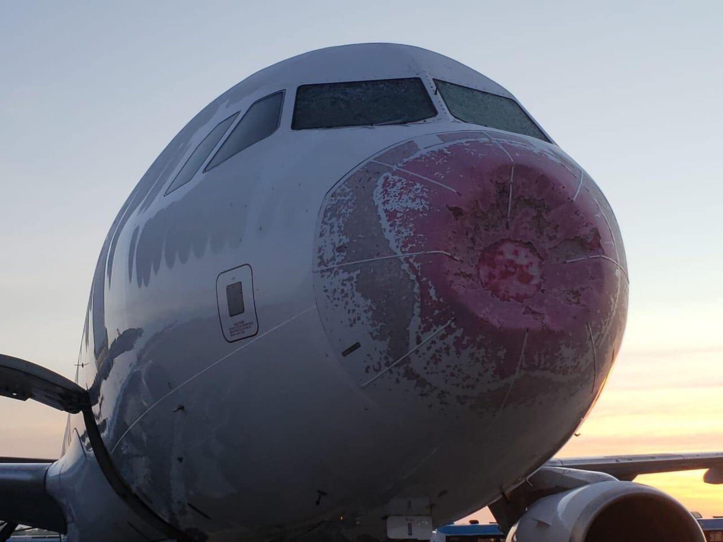 Flight JJ-8050 experienced turbulence and hail that caused both windshields to crack and a damaged nose cone.