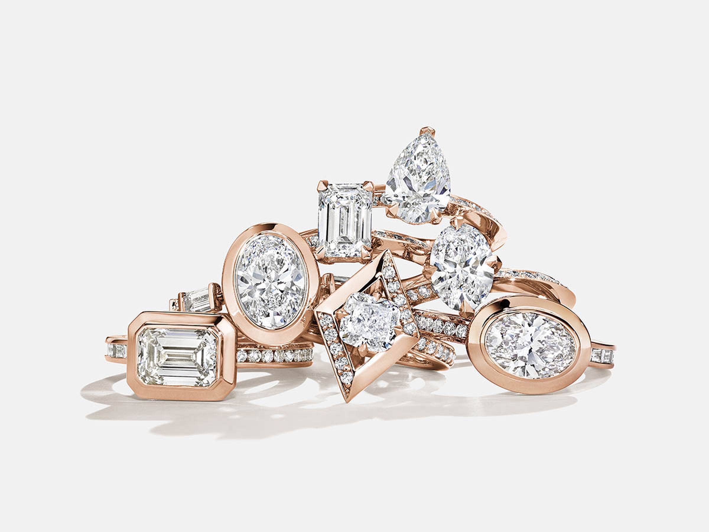 A pile of diamond and rose gold rings against a white background.