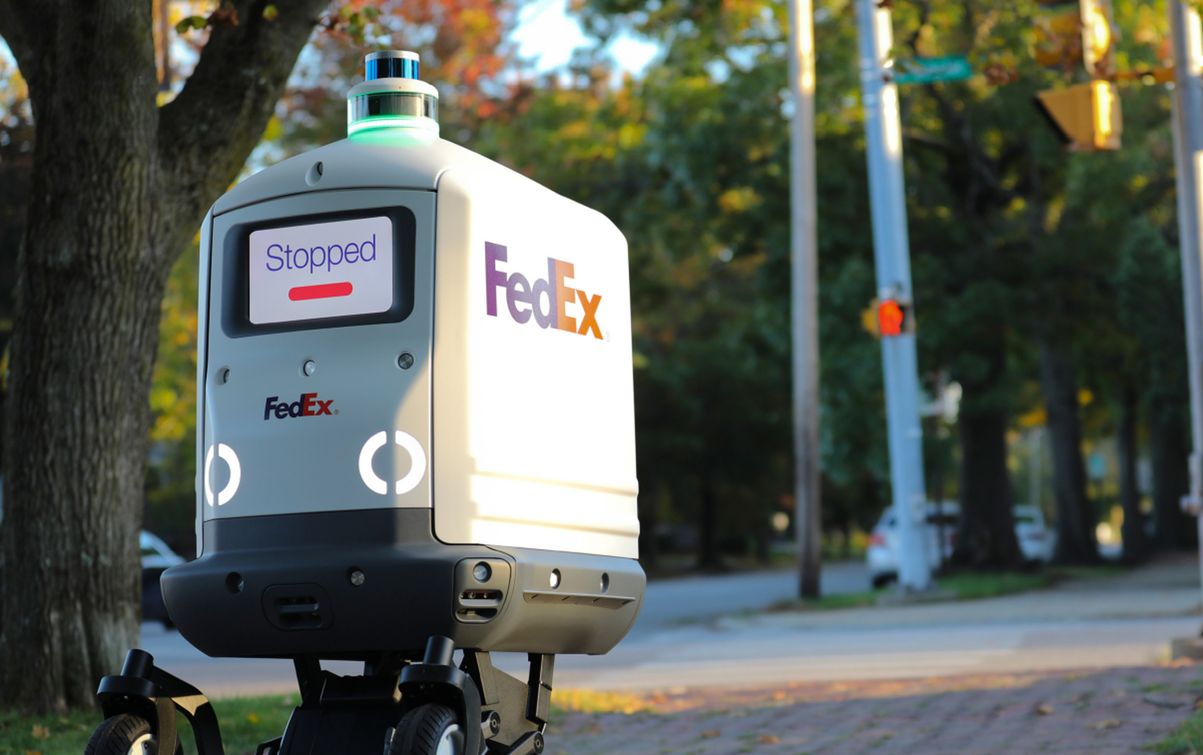 A photograph of a delivery robot with a screen on the front saying “Stopped.”