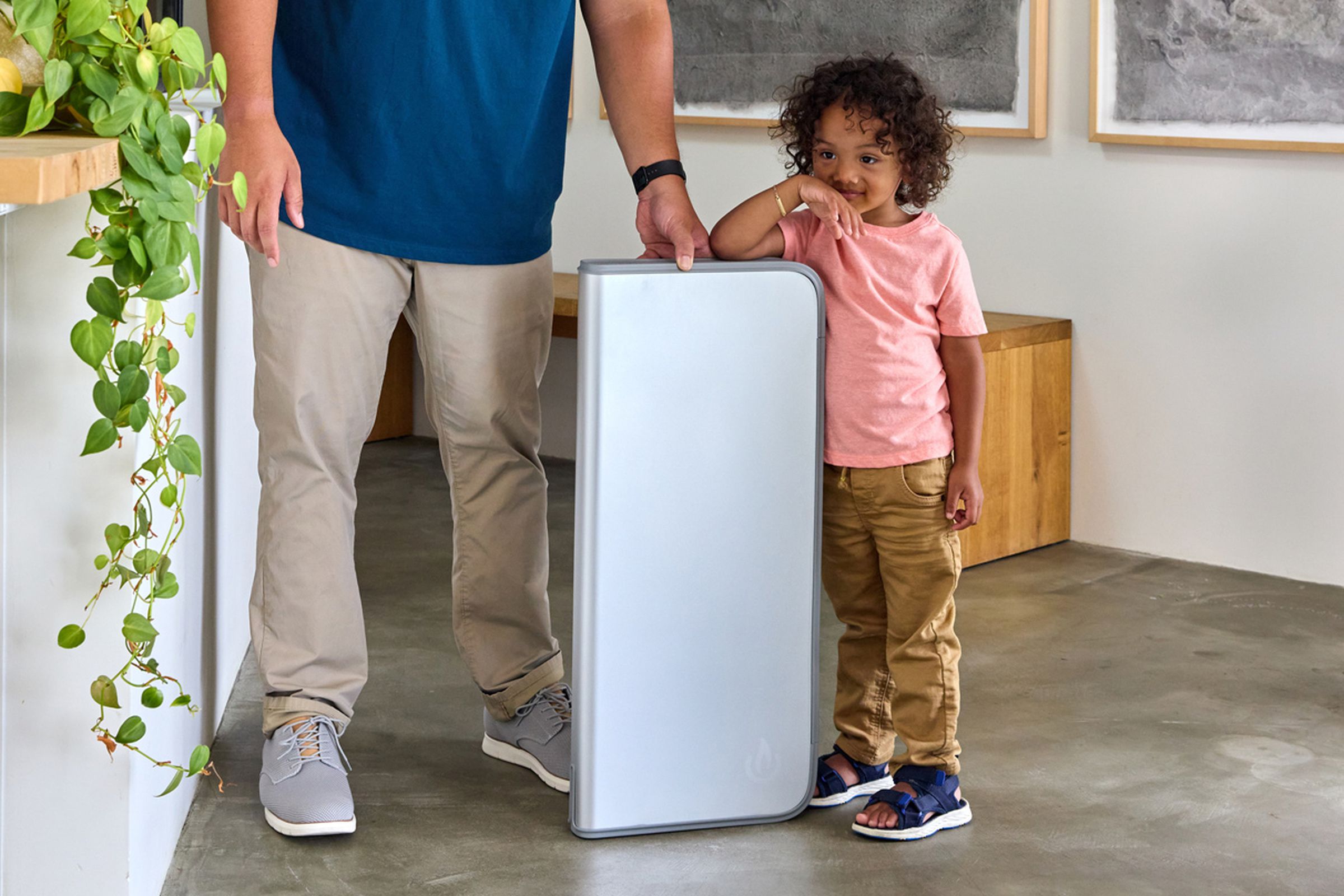 A child standing next to a Backup by BioLite battery help up by an adult.