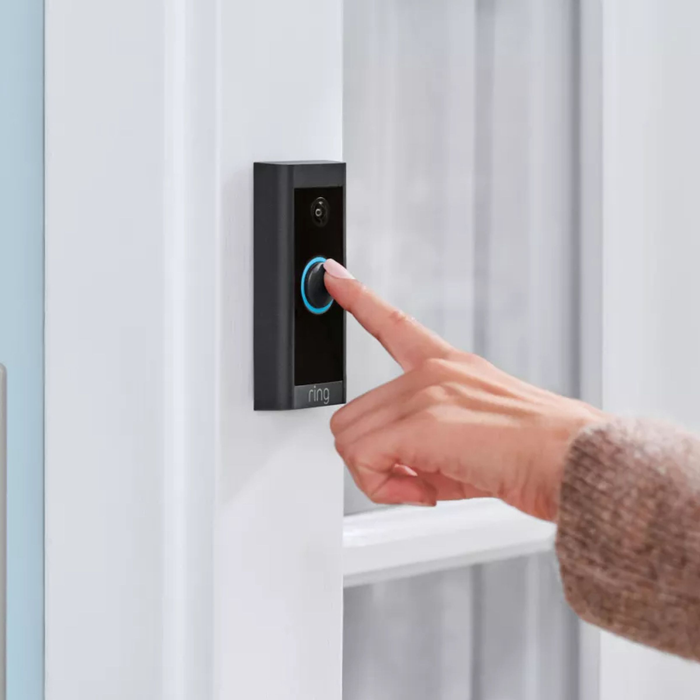 An outstretched hand pressing the Ring Video Doorbell.