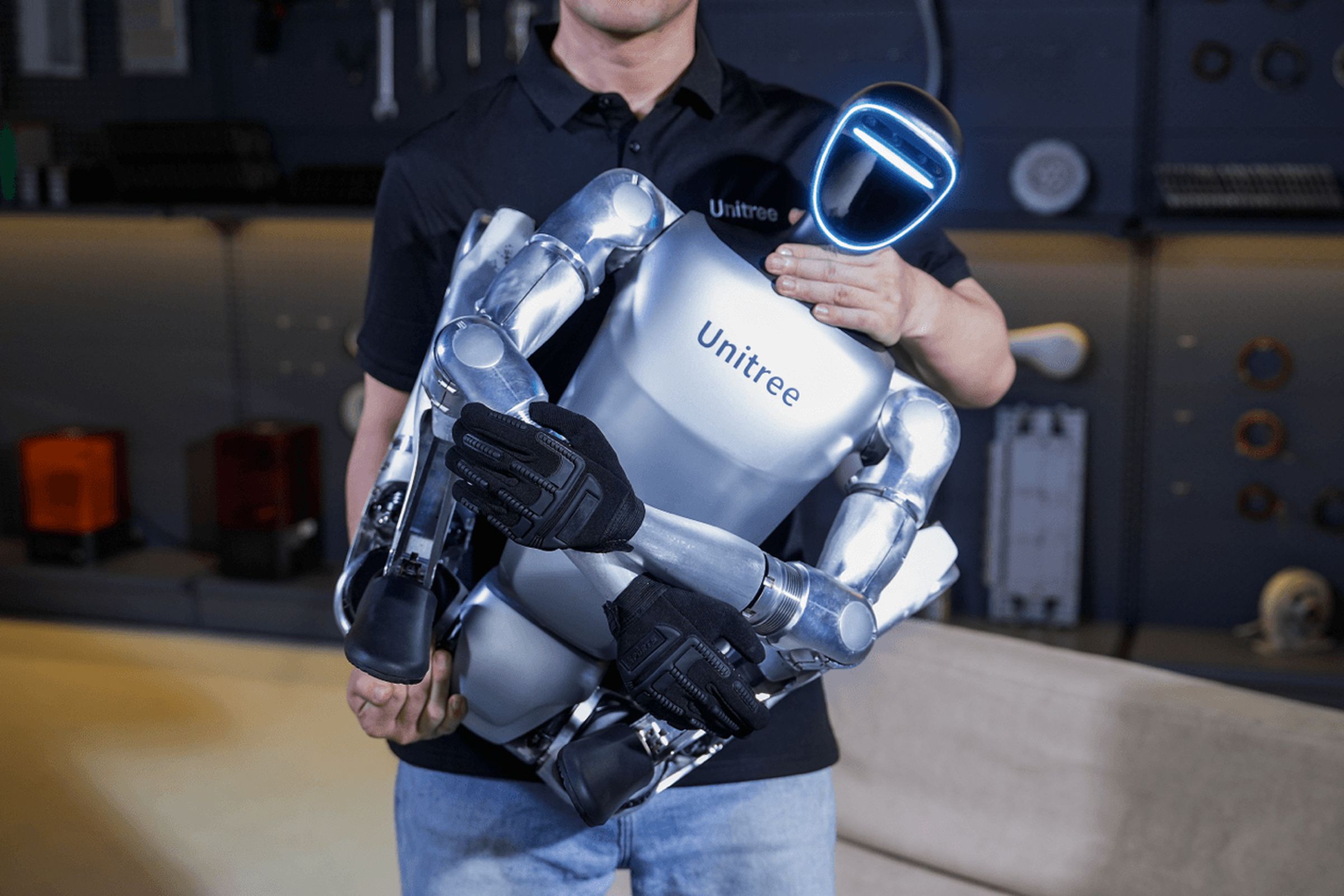 A person holding the Unitree G1 humanoid robot in its folded state.