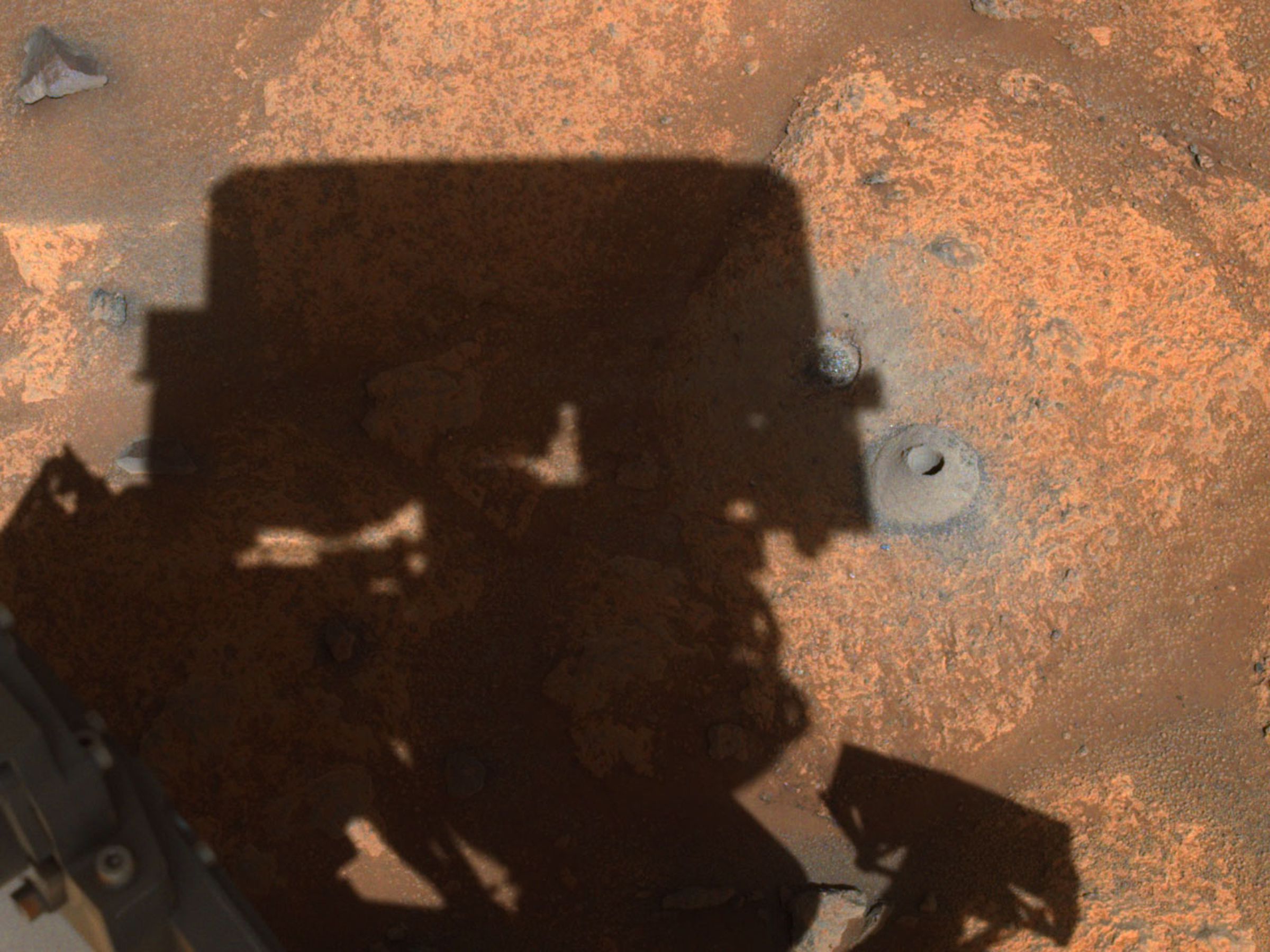 The hole Perseverance drilled on August 5th sitting to the right of the shadow of the rover’s turret.