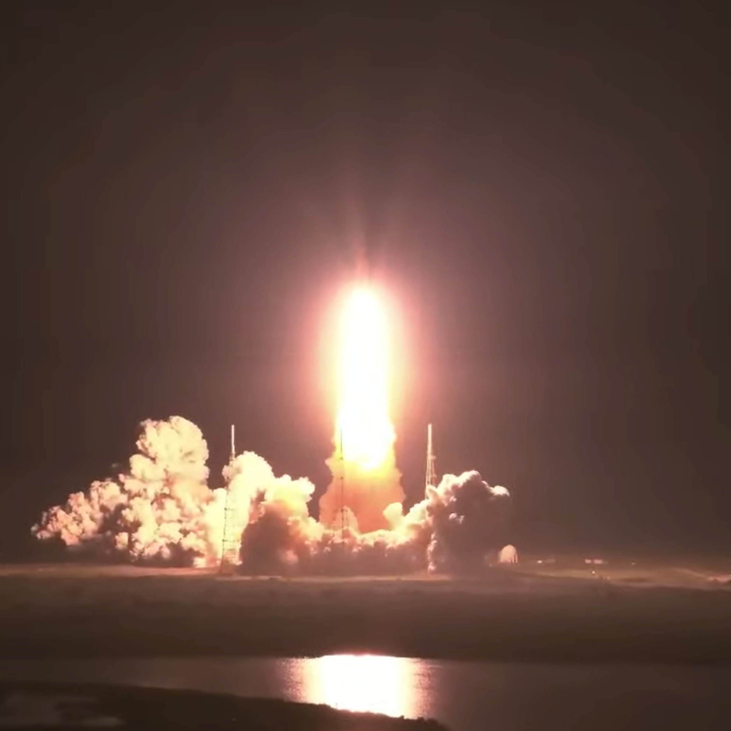 A rocket launches against a dark black sky. 