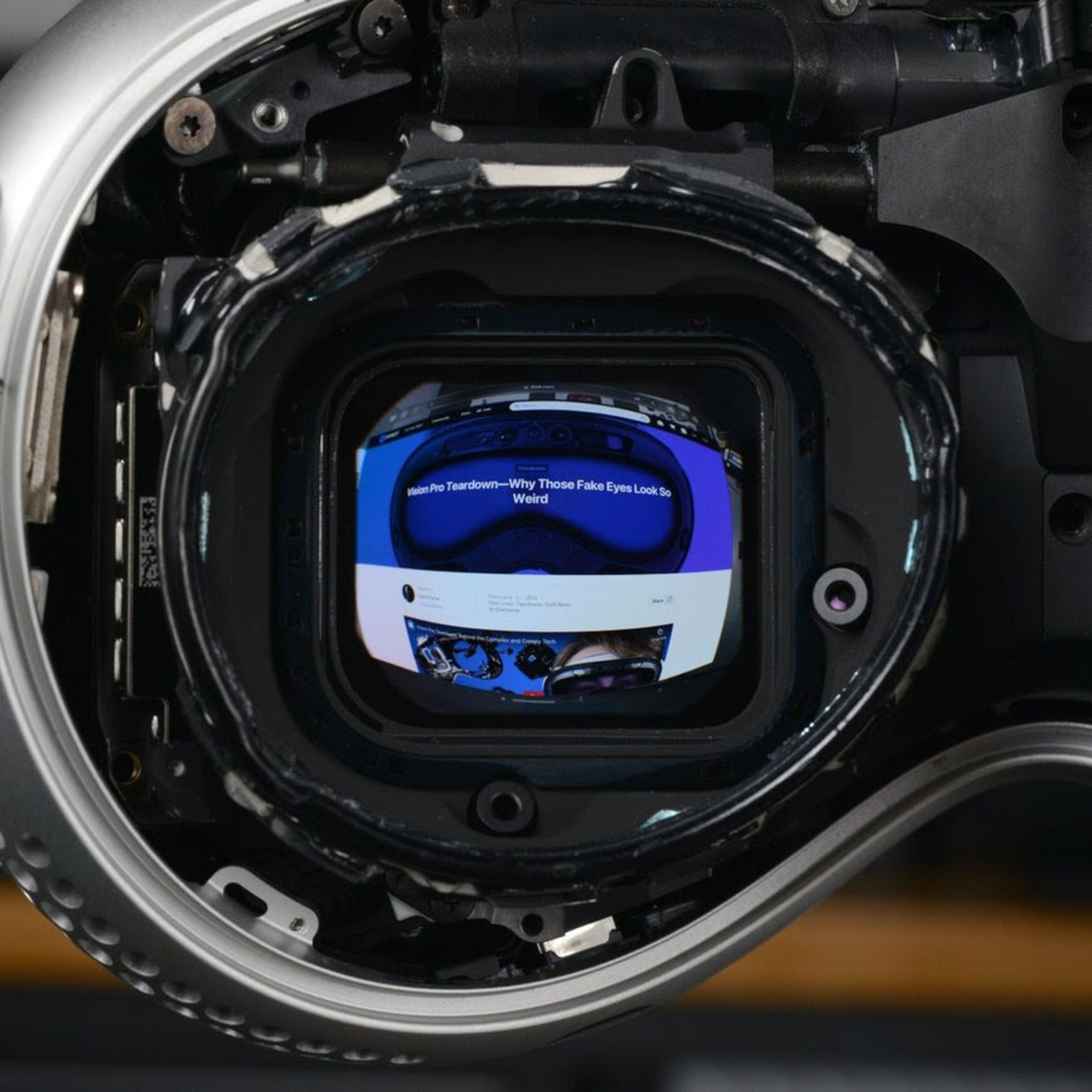 A close look at the left eye display of a Vision Pro headset with several parts removed.