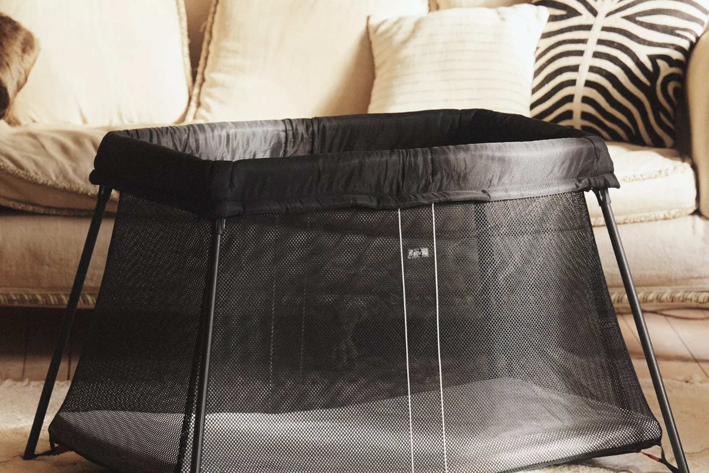 سرير شبكي أسود مع مرتبة وأريكة في الخلفية.