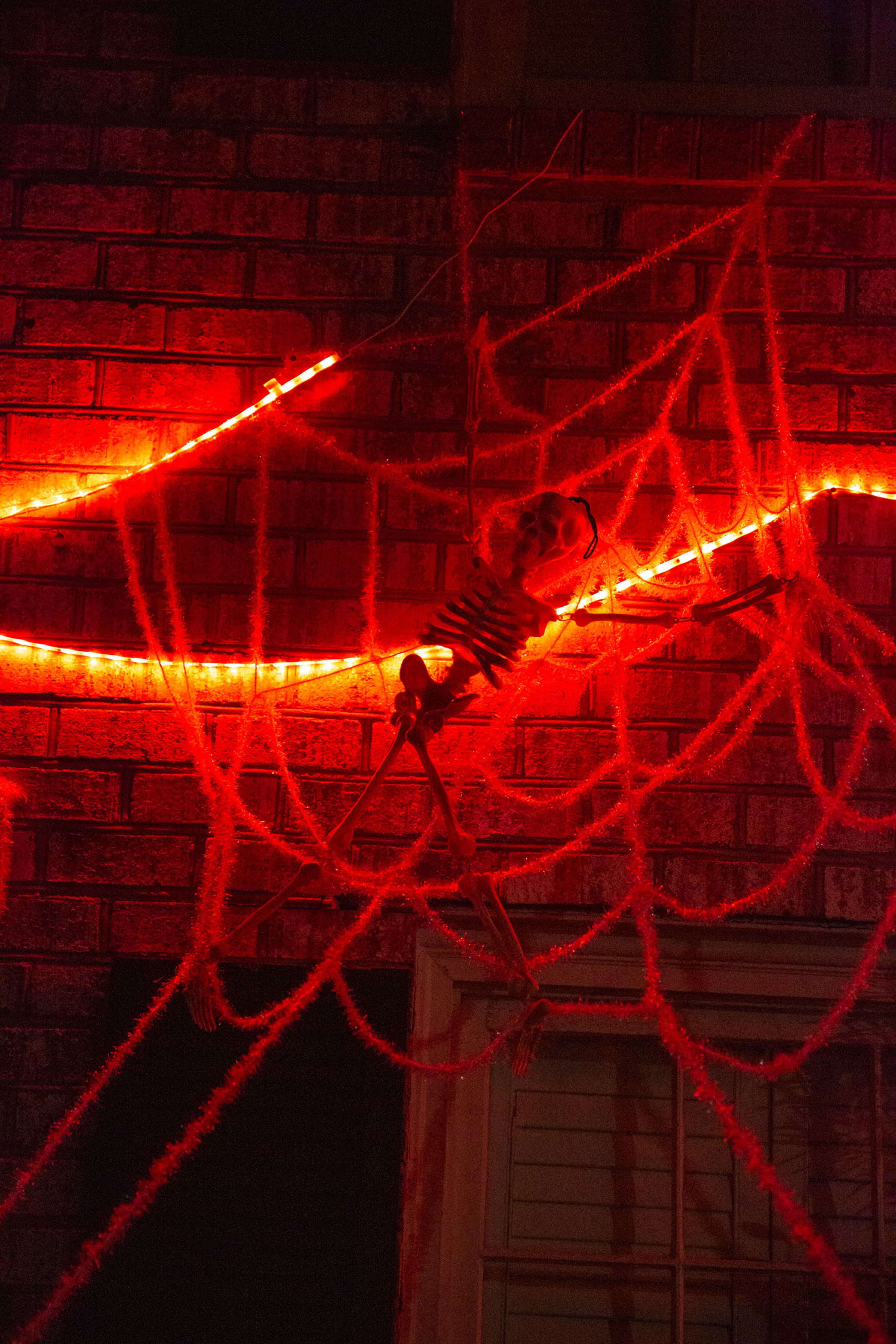 A plastic skeleton in a fake spider web on the side of a house