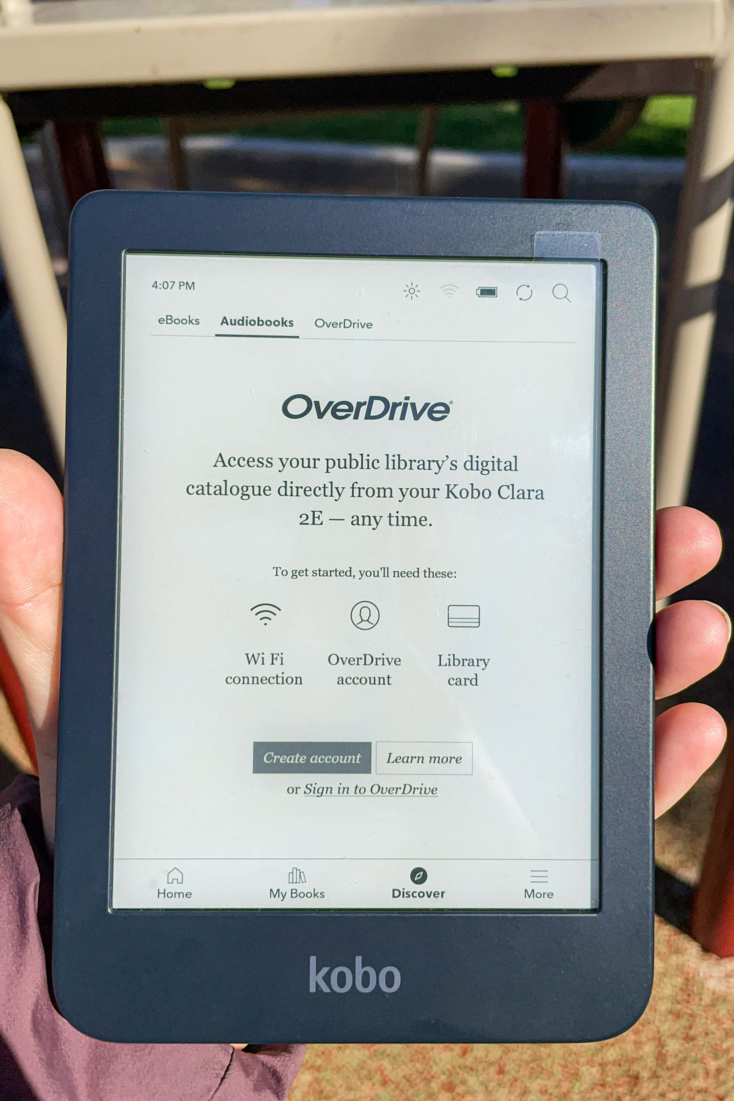 A hand holding up the Kobo Clara 2E with the OverDrive tab on display.
