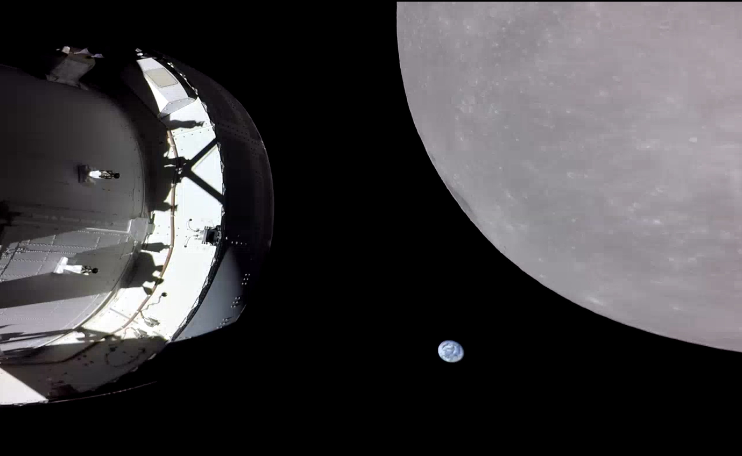 The Orion capsule sits in shadow to the left. To the right, the grey bulk of the Moon dominates the image. Between the two, Earth appears as a small blue and white ball. 