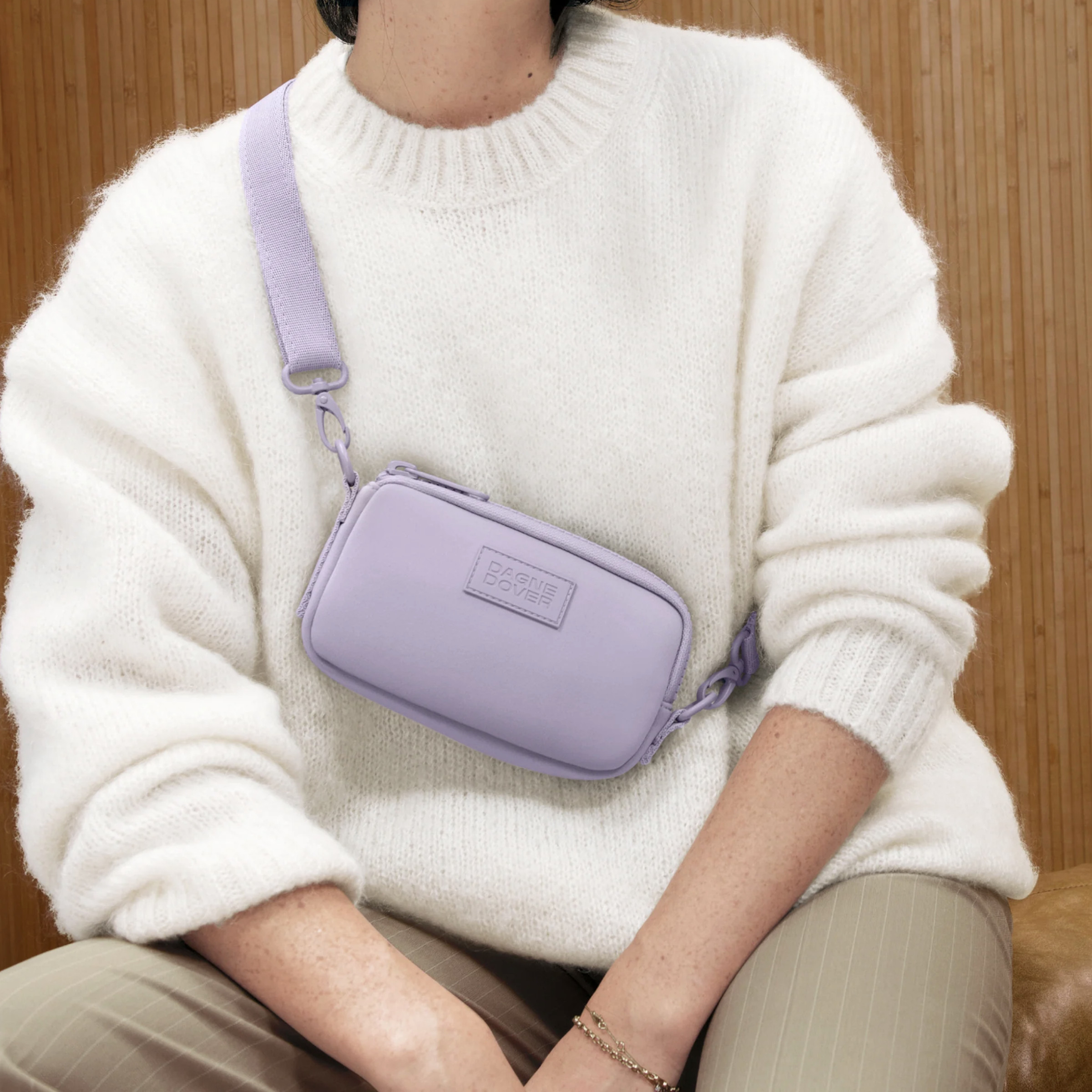 Person in white sweater where lavender sling bag.