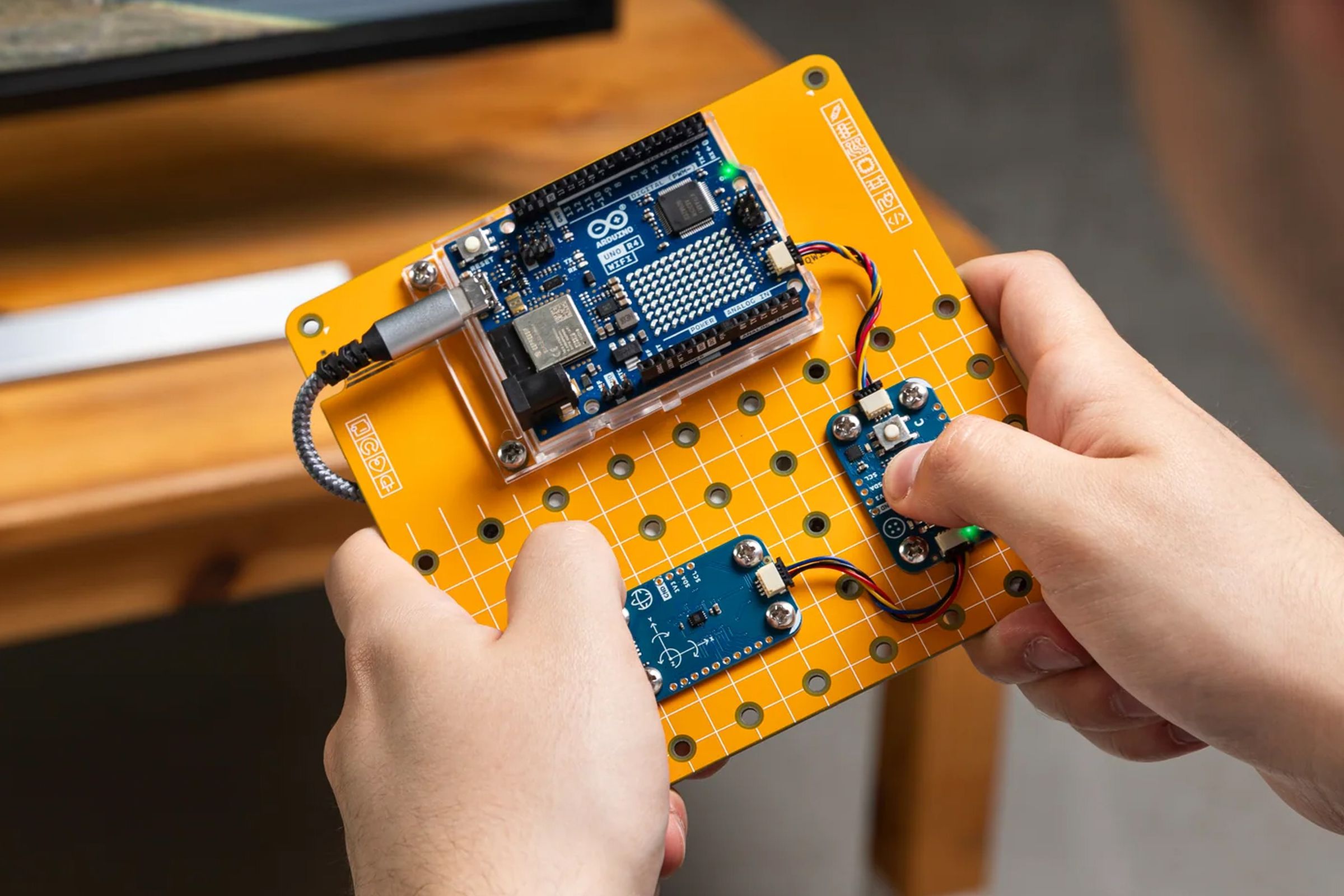 A user plays a video game using a game controller assemble from the Arduino Plug and Make Kit.