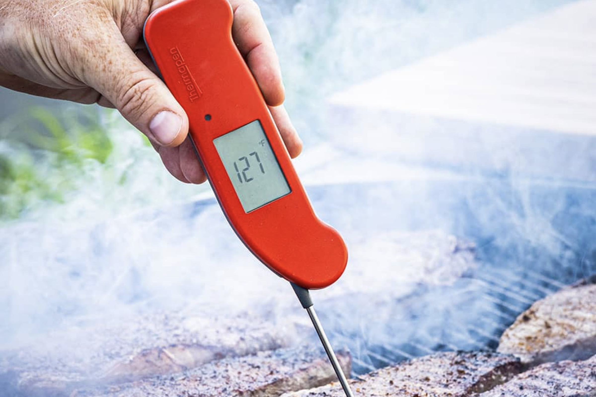 Hand holding Thermapen One thermometer into a grilled steak.