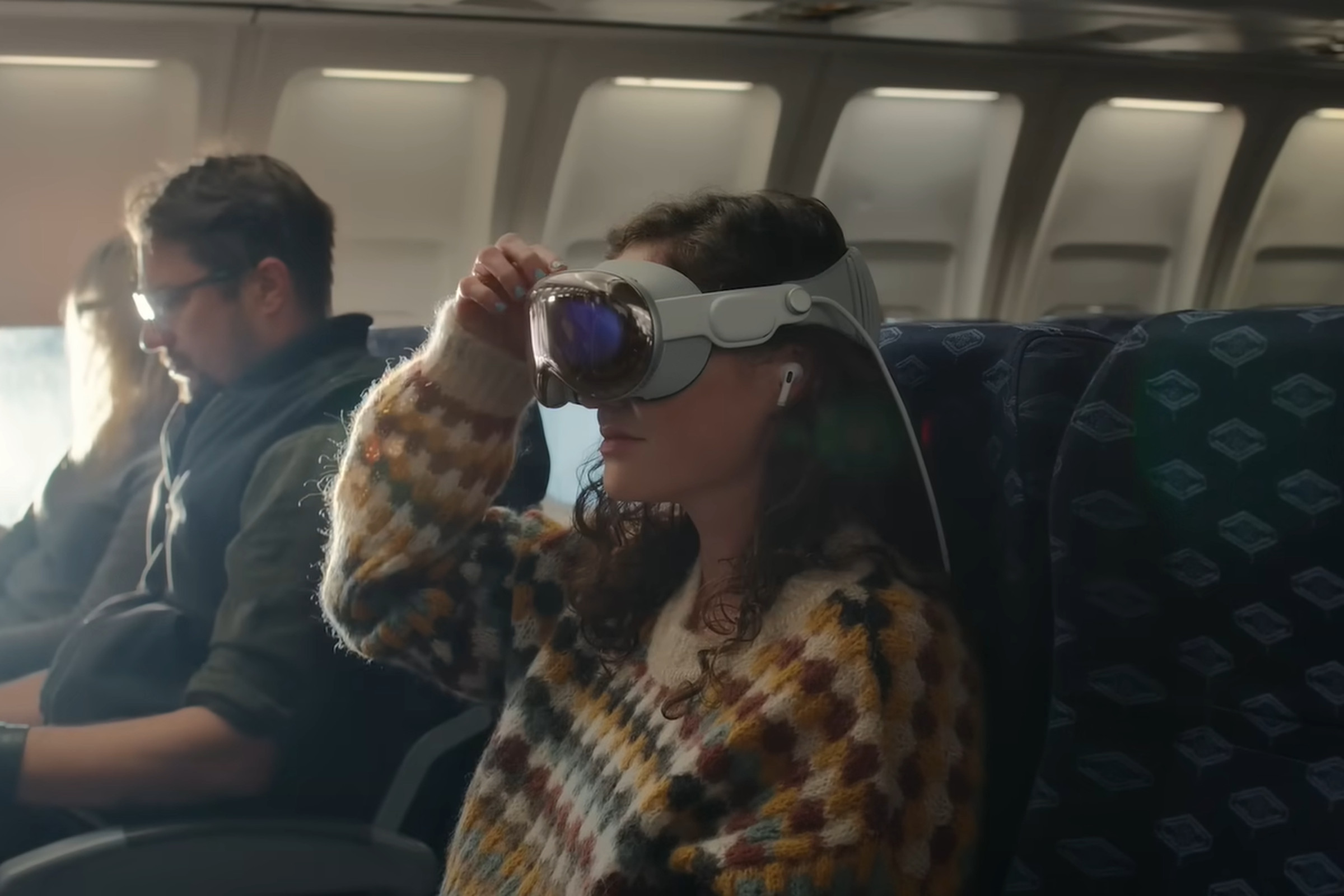 An image of a woman wearing Apple’s Vision Pro headset and AirPods Pro on a plane.