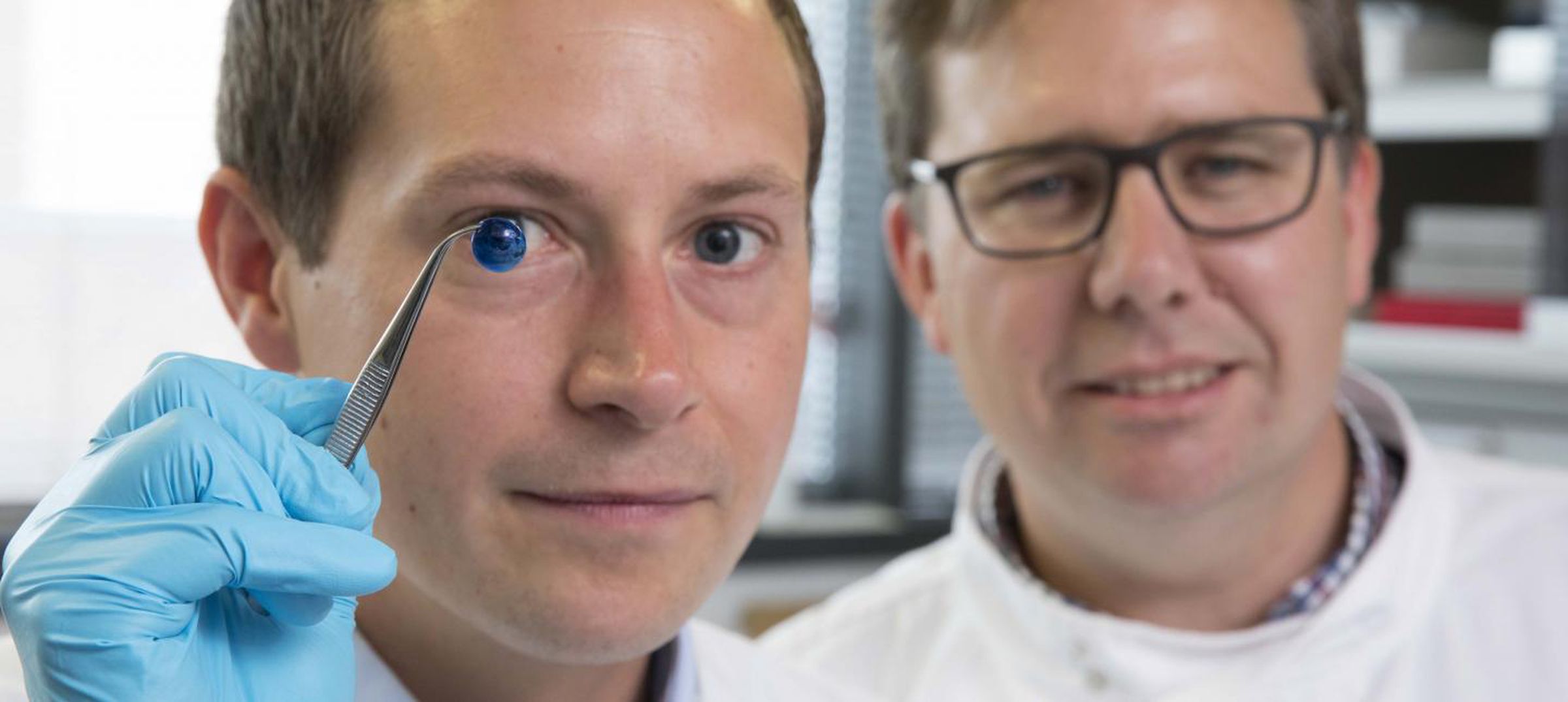 Two of the creators of the artificial cornea, Steve Swioklo and Professor Che Connon. Swioklo is holding up a dyed cornea.