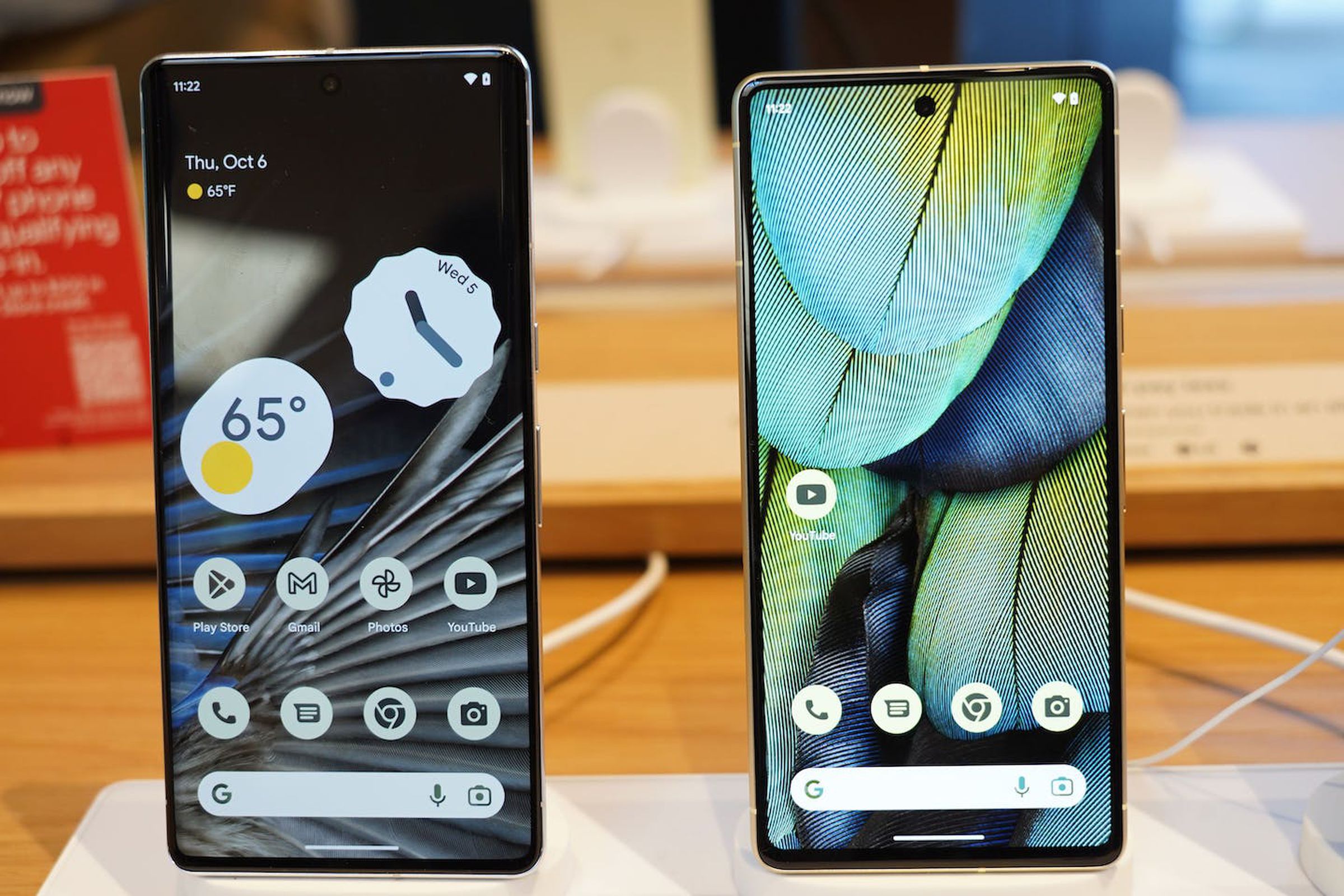 The bigger Pixel 7 Pro (left) and Pixel 7 (right) standing upright while turned on.