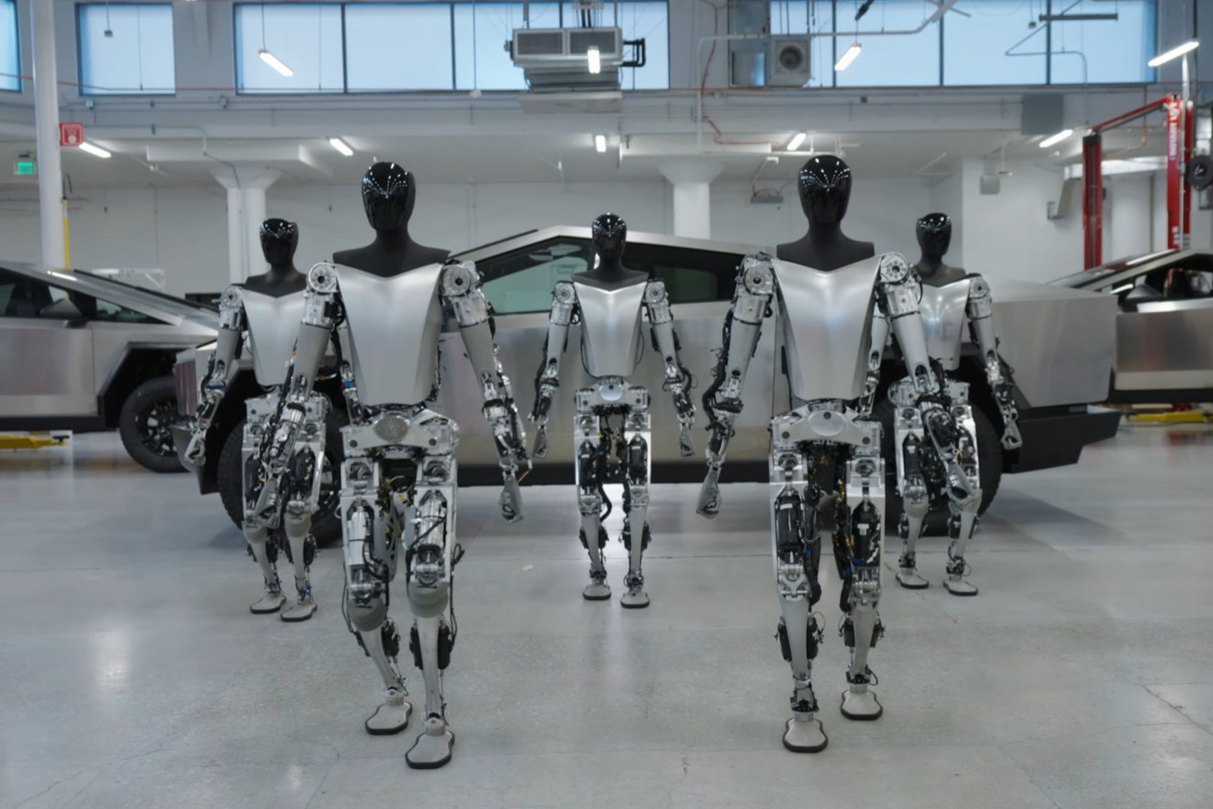 Tesla Bots shown walking in front of a Cybertruck