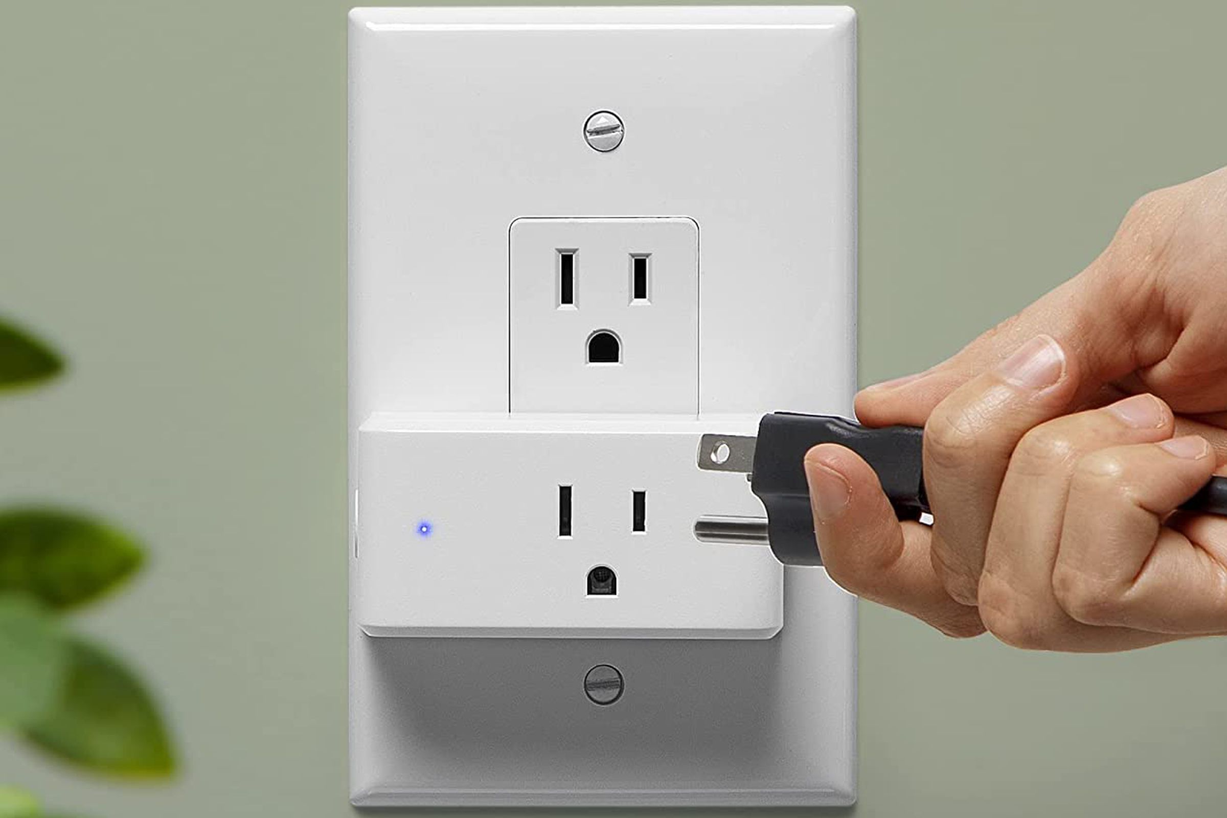 A photo of the iHome Smart plug with a hand plugging in a power cord