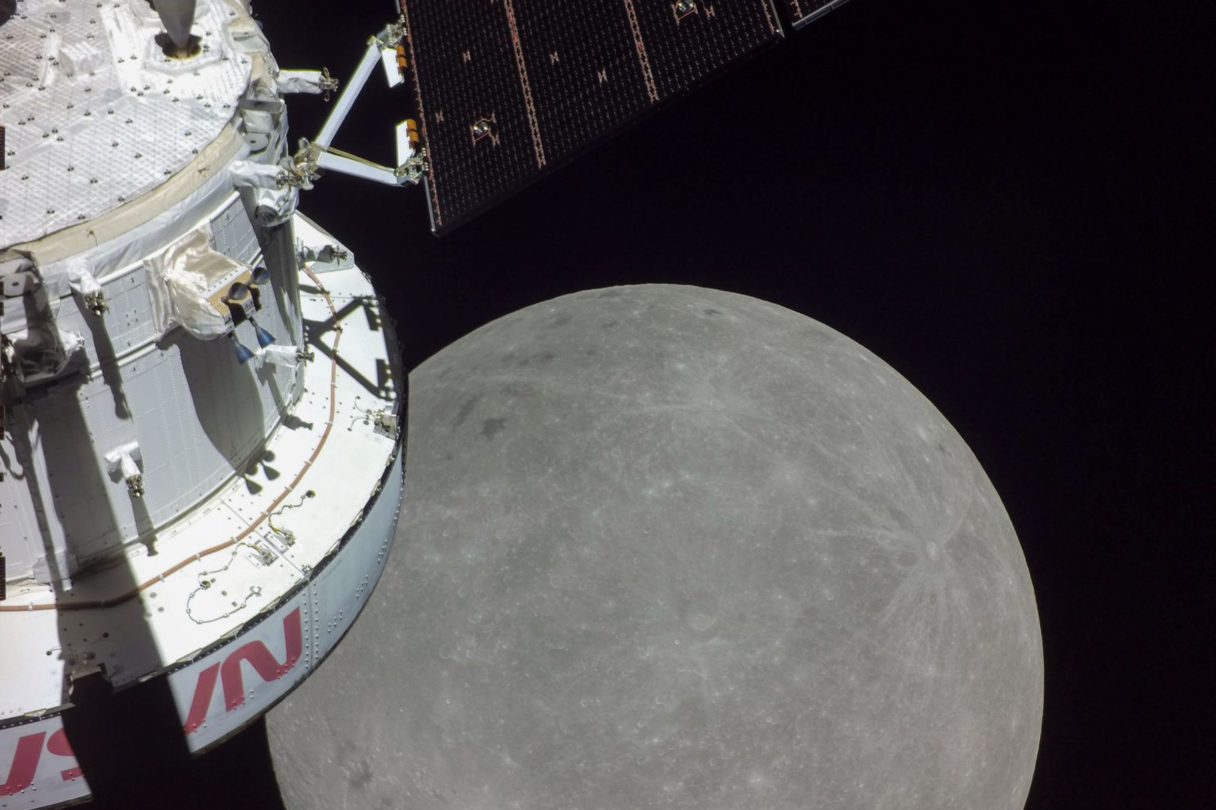 A white spacecraft with NASA’s logo in red is on the left with the disc of the moon in the center.