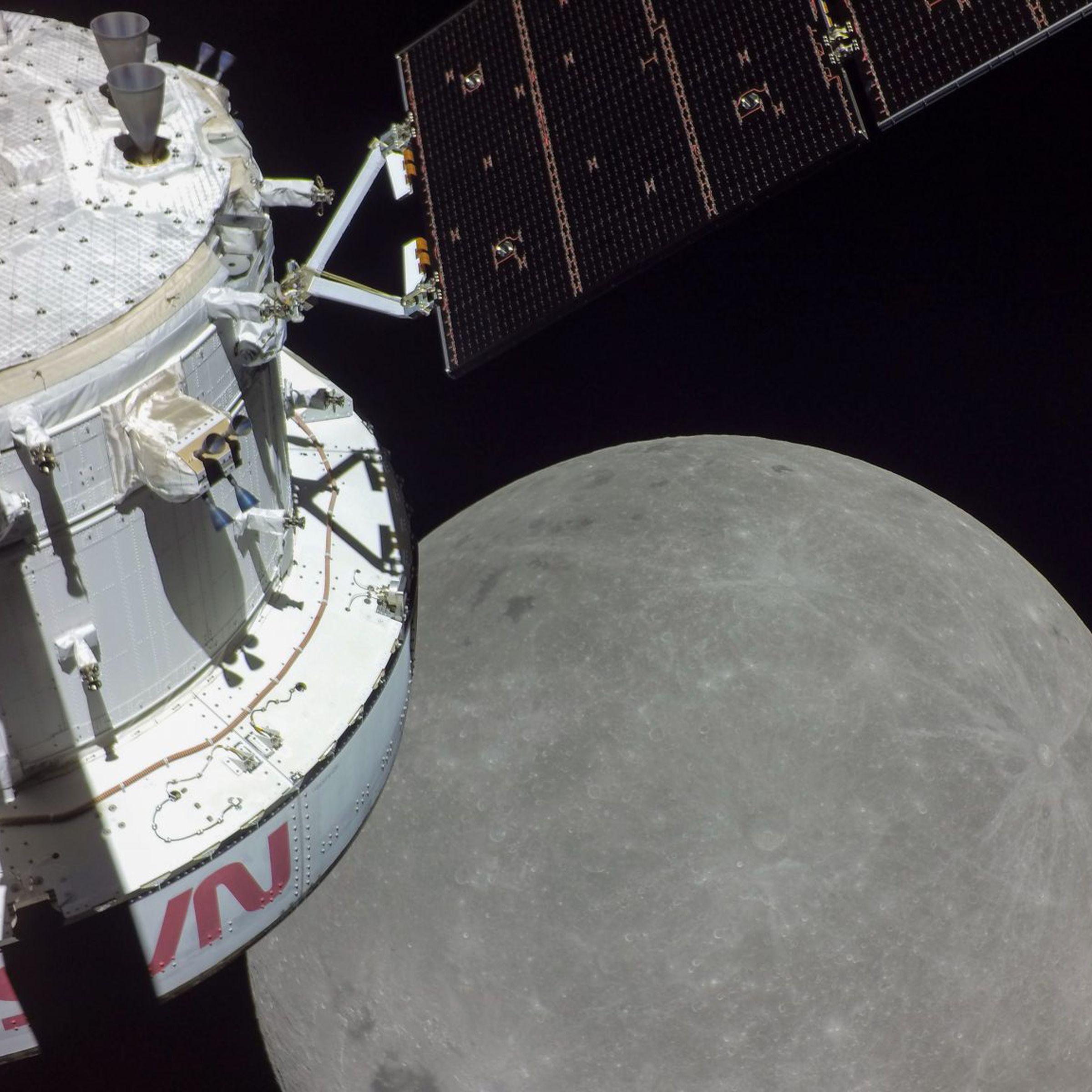 A white spacecraft with NASA’s logo in red is on the left with the disc of the moon in the center.