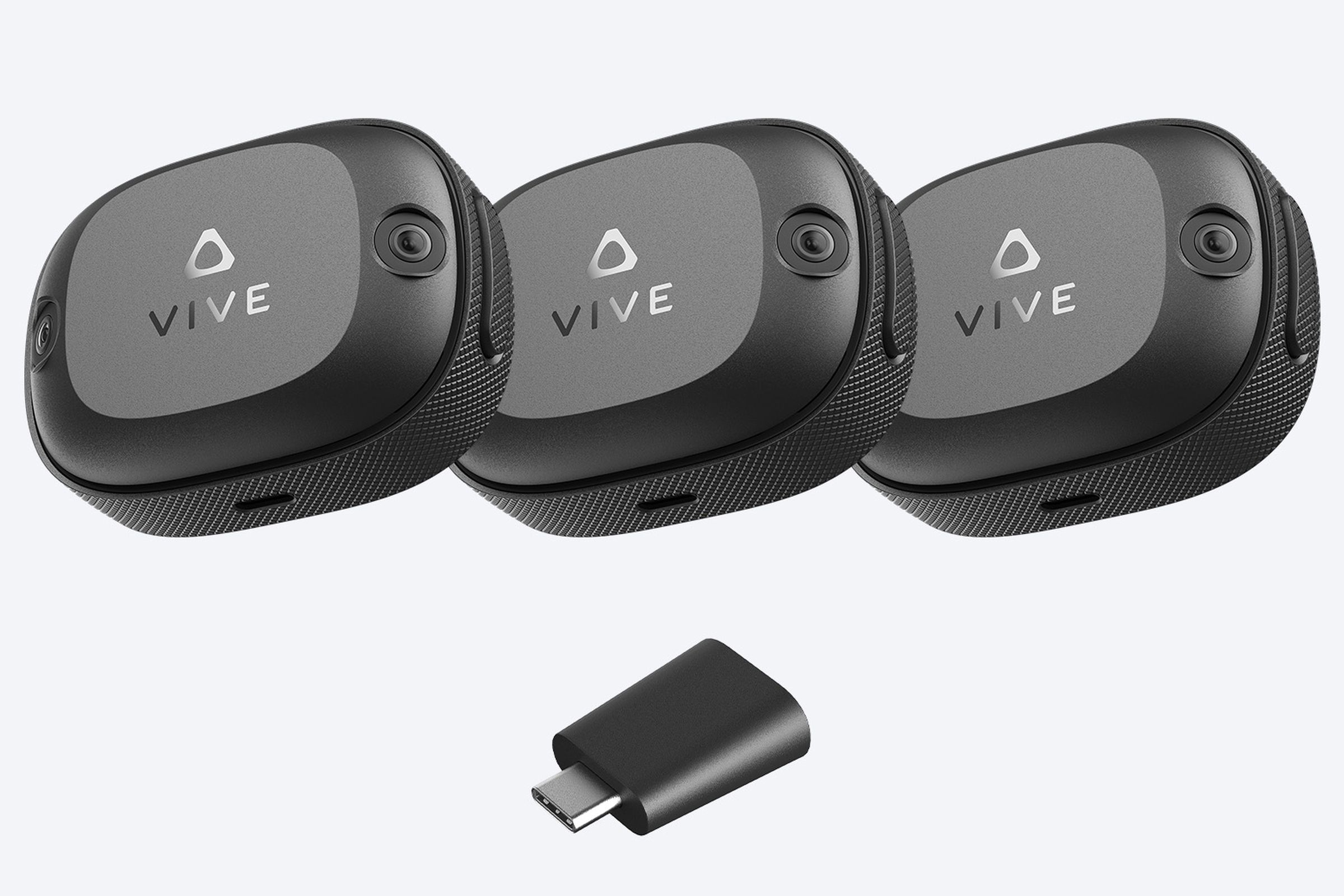 Three Vive Ultimate trackers and their wireless dongle.