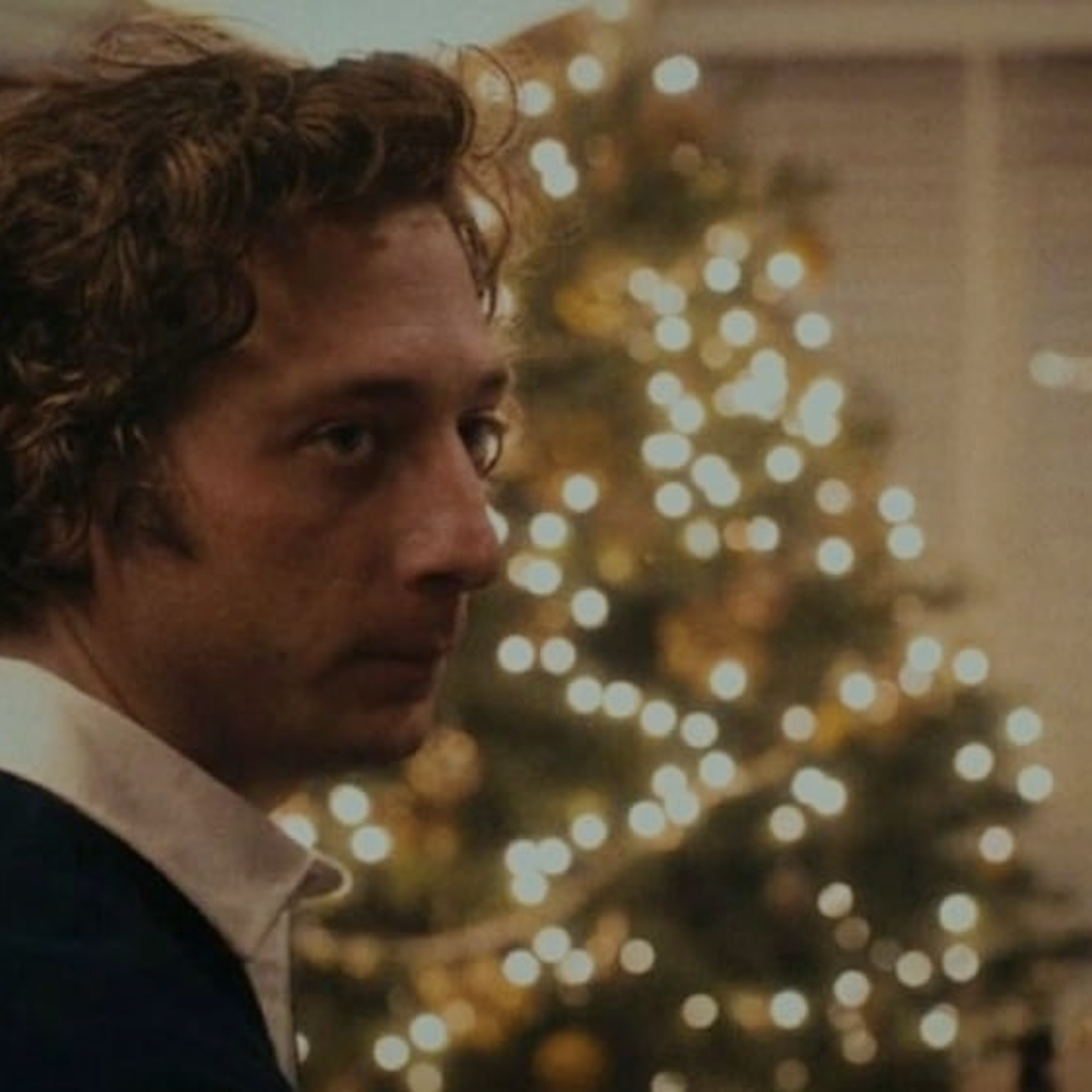 Jeremy Allen White from The Bear with a Christmas tree in the background.