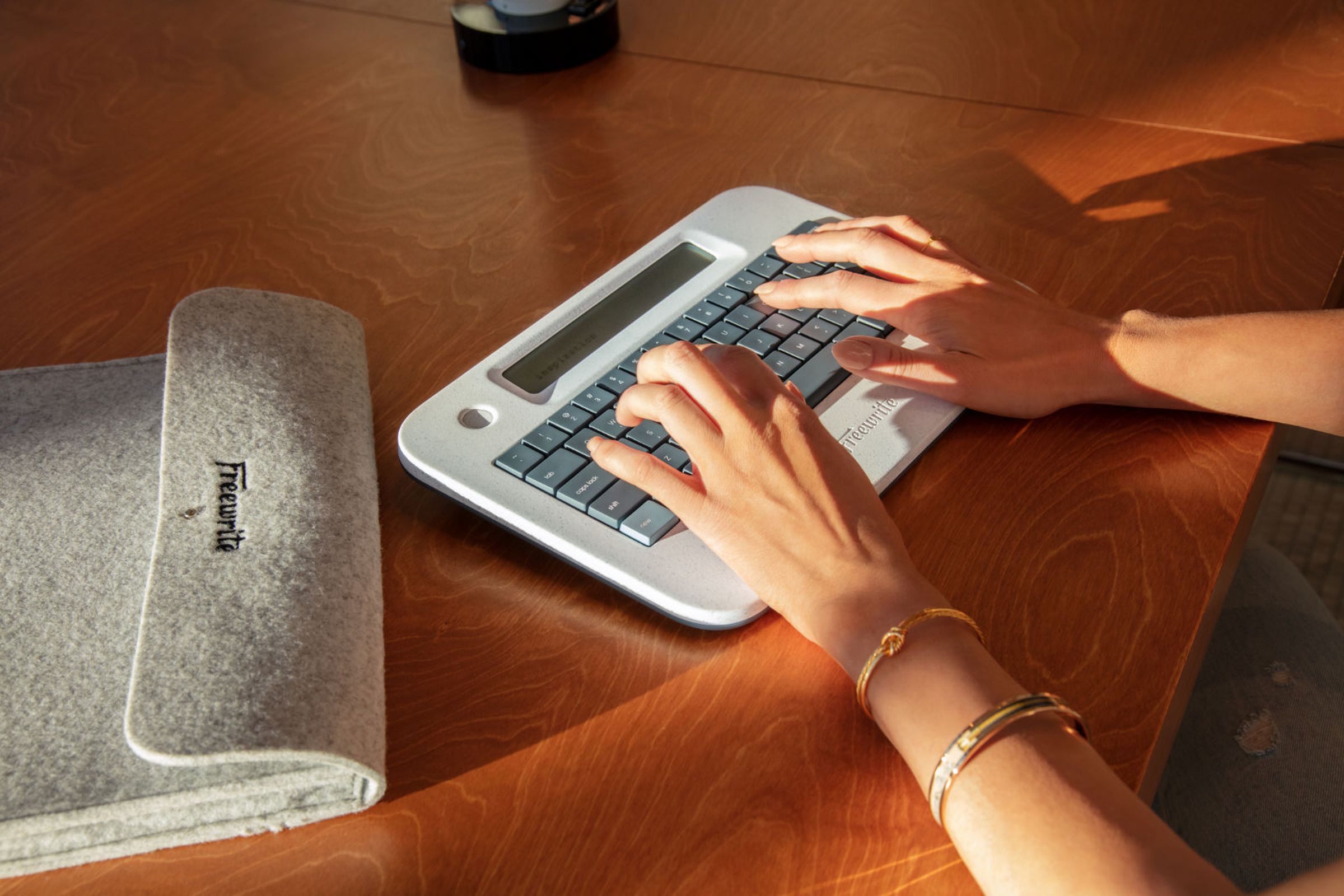 A pair of hands using the Freewrite Alpha typewriter