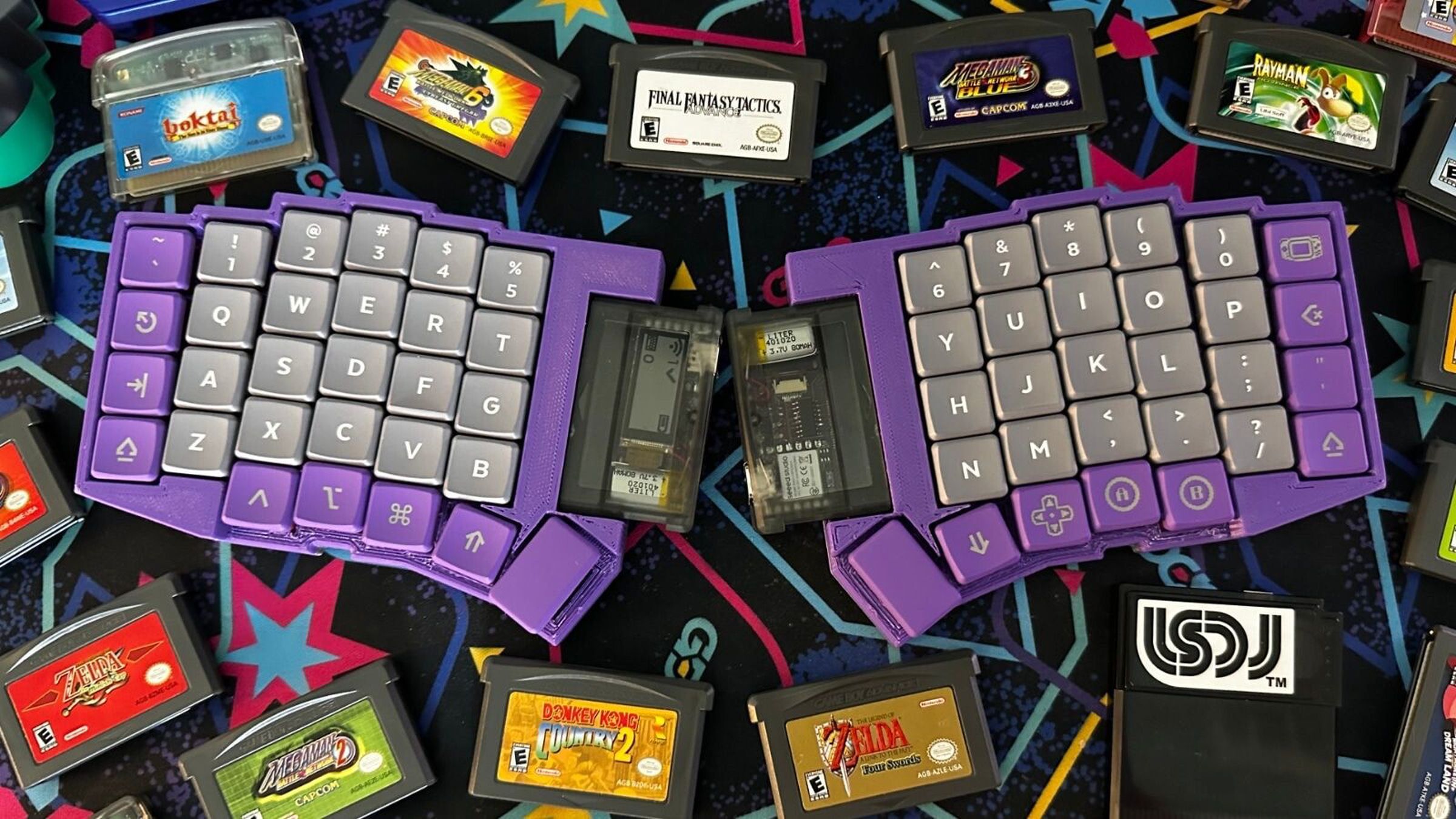 Overhead shot of a split wireless mechanical keyboard. It has an ortho staggered layout, a 3D printed purple chassis, purple modifier keys, white-on-grey alpha legends, and a translucent Game Boy Advance cartridge on each side holding its microcontrollers.