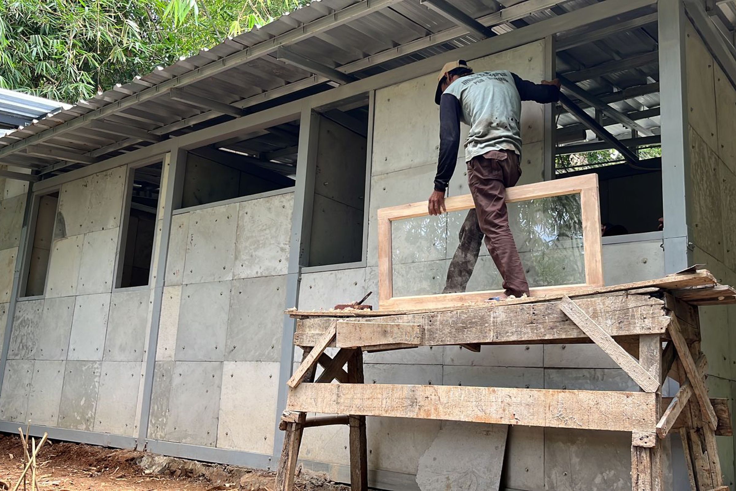 A person stands on a platform next to a small house under construction.