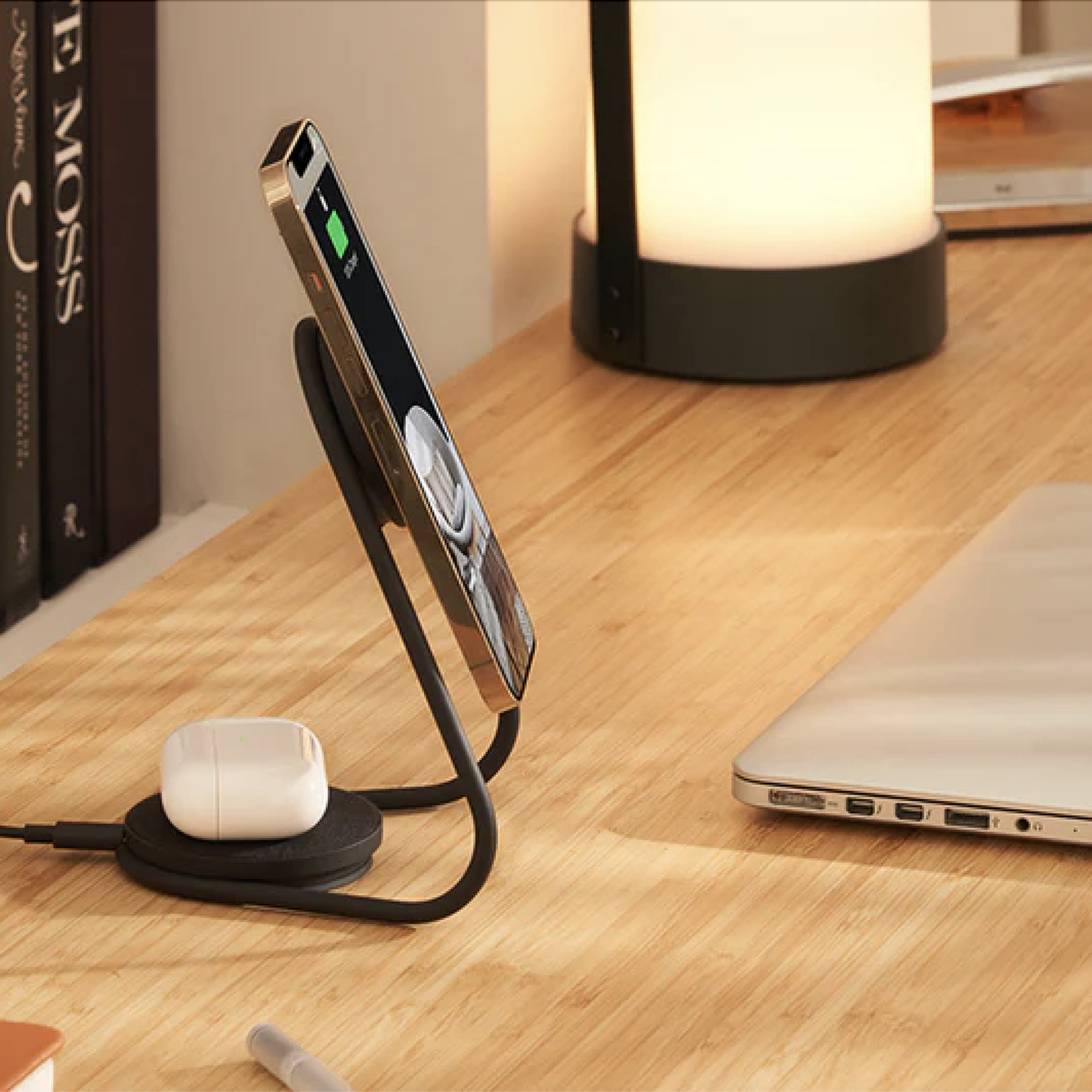 Metallic stand on a desk holding an iphone and, in back, an AirPods case.