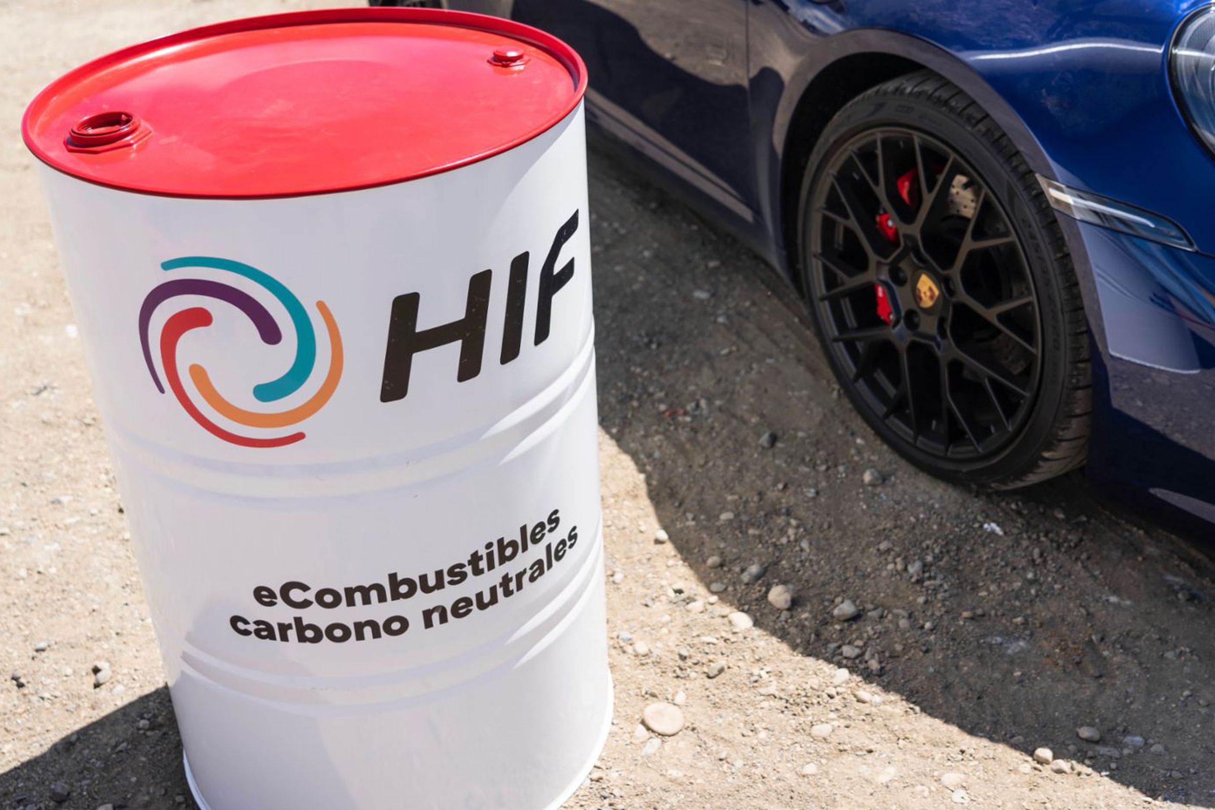 A barrel of fuel next to the front of a car.